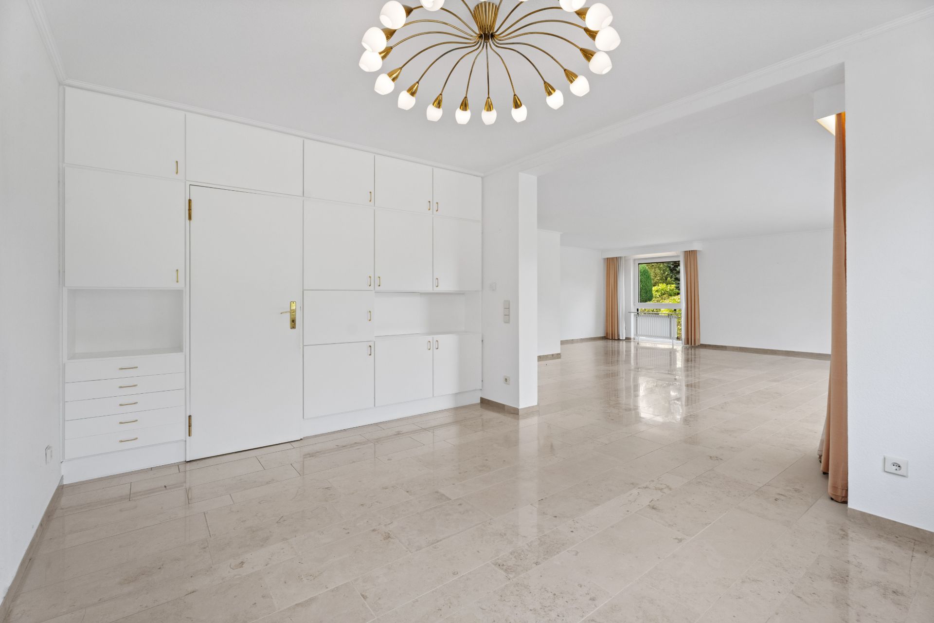 Helles Wohnzimmer mit Einbauschränken, Kronleuchter und großen Fenstern.