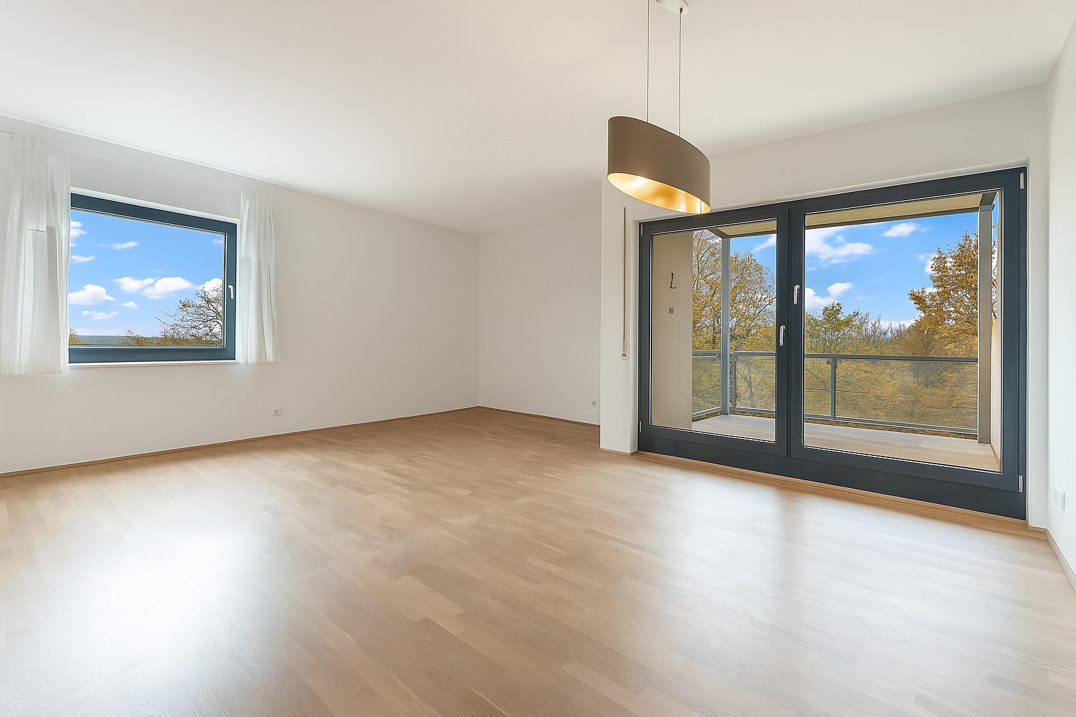 Helles Wohnzimmer mit Parkettboden, Fenster, großer Glastür und Blick auf einen Balkon.