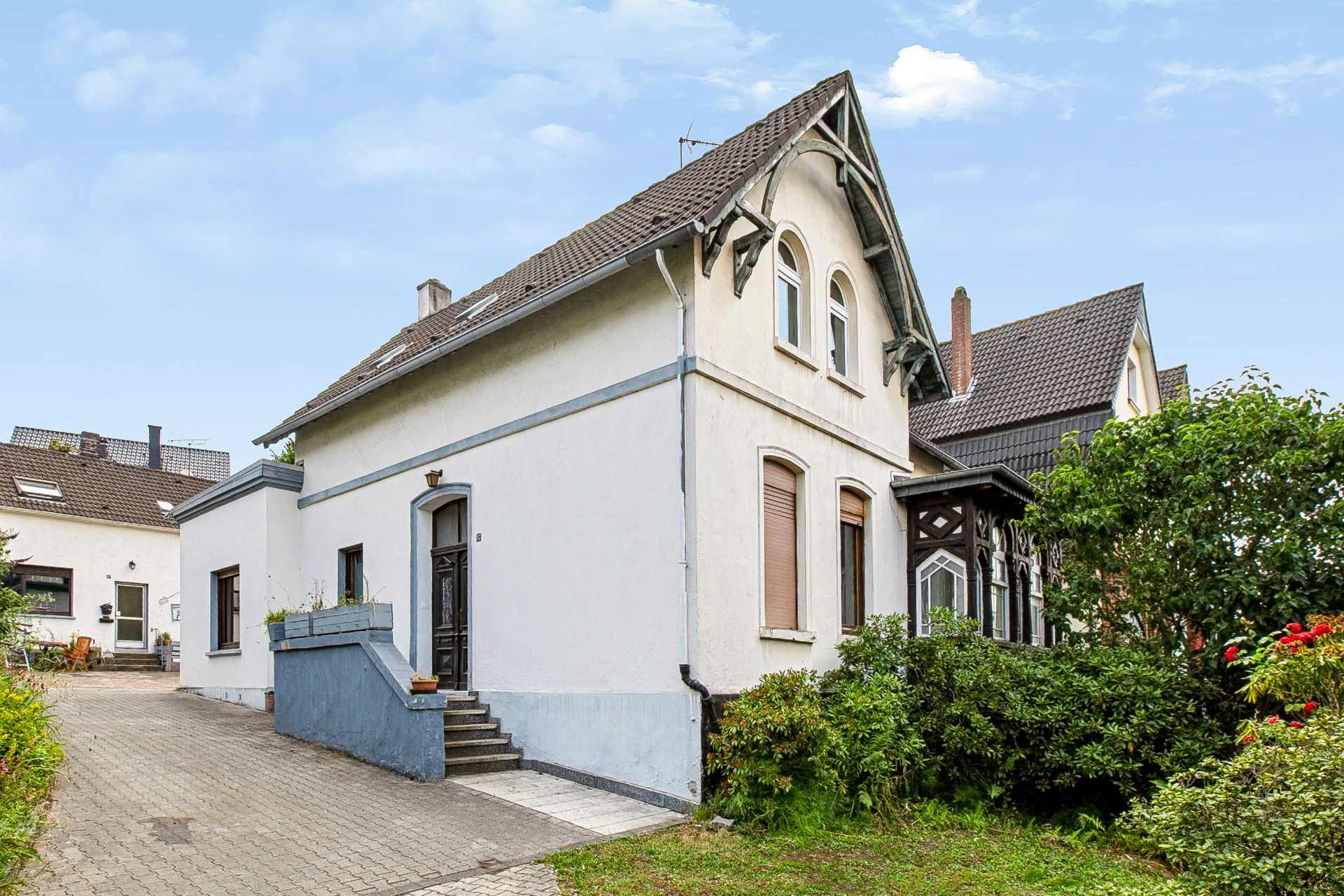 Weißes Einfamilienhaus mit Satteldach, Eingangstreppe und kleinem Vorgarten.