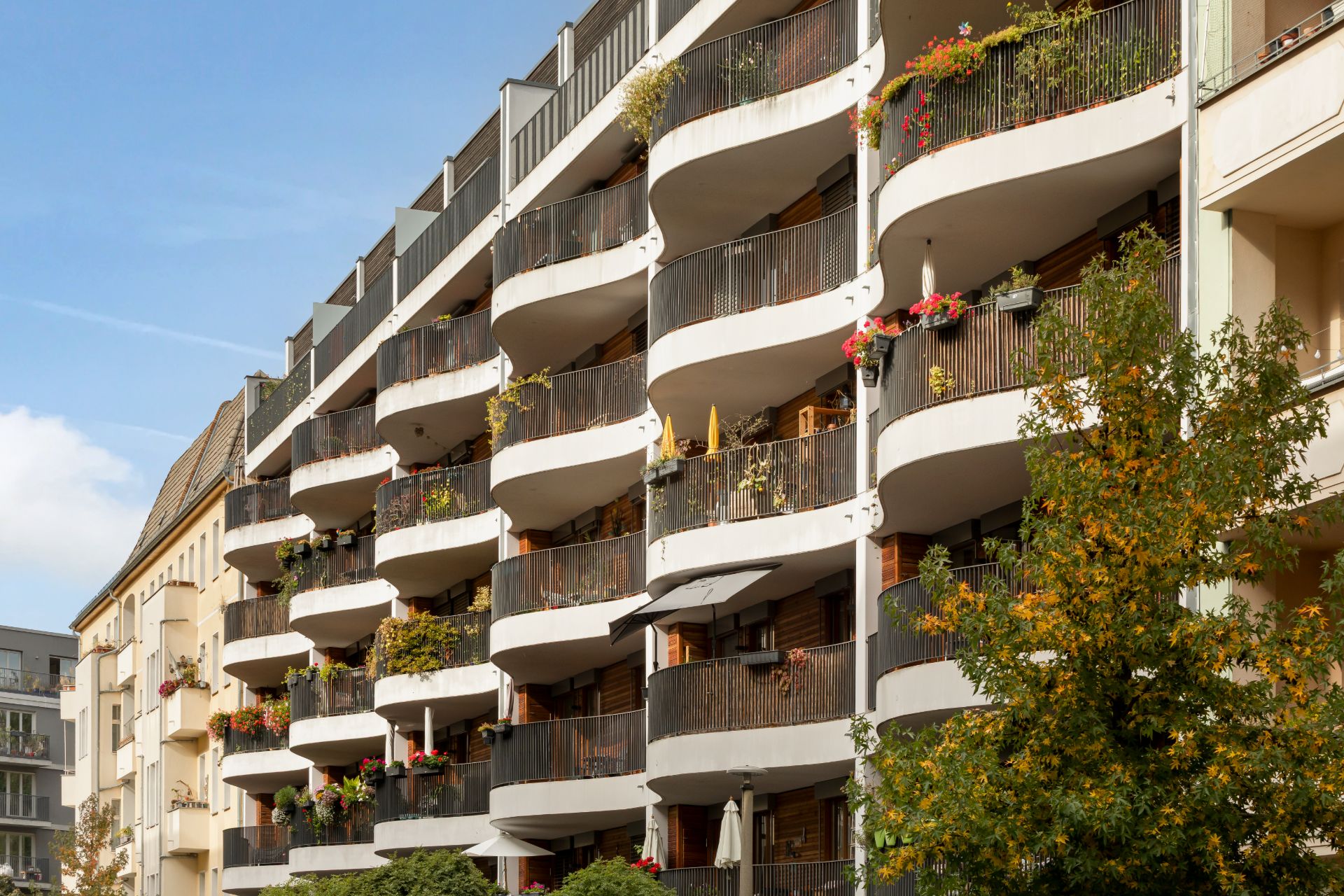 Mehrstöckiges Wohnhaus mit geschwungenen Balkonen und Blumen an den Geländern.
