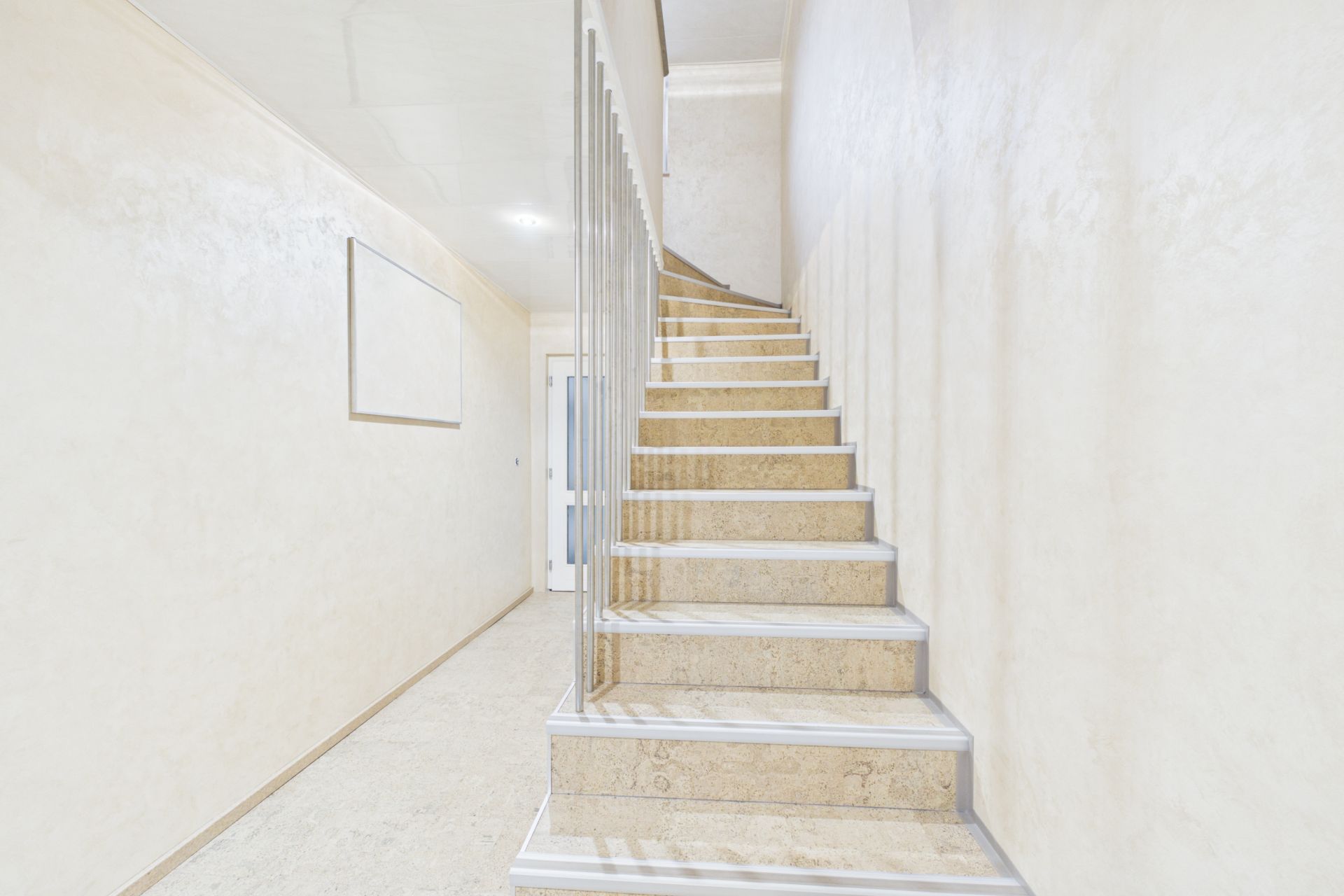 Helles Treppenhaus mit beigen Wänden und Marmortreppe in einem Wohnhaus.
