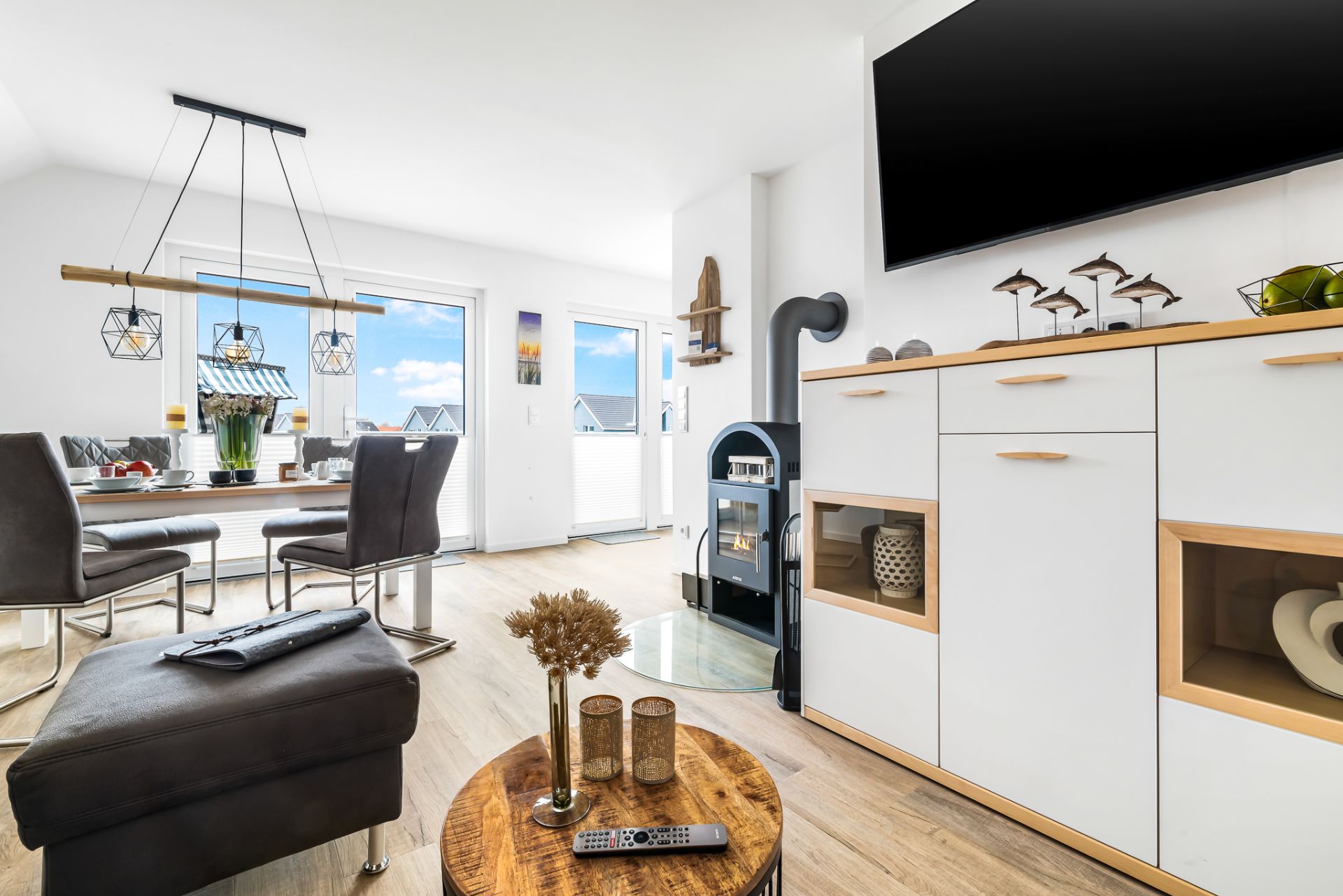 Helles Wohnzimmer mit Esstisch, Kamin, Fernseher und moderner Einrichtung.