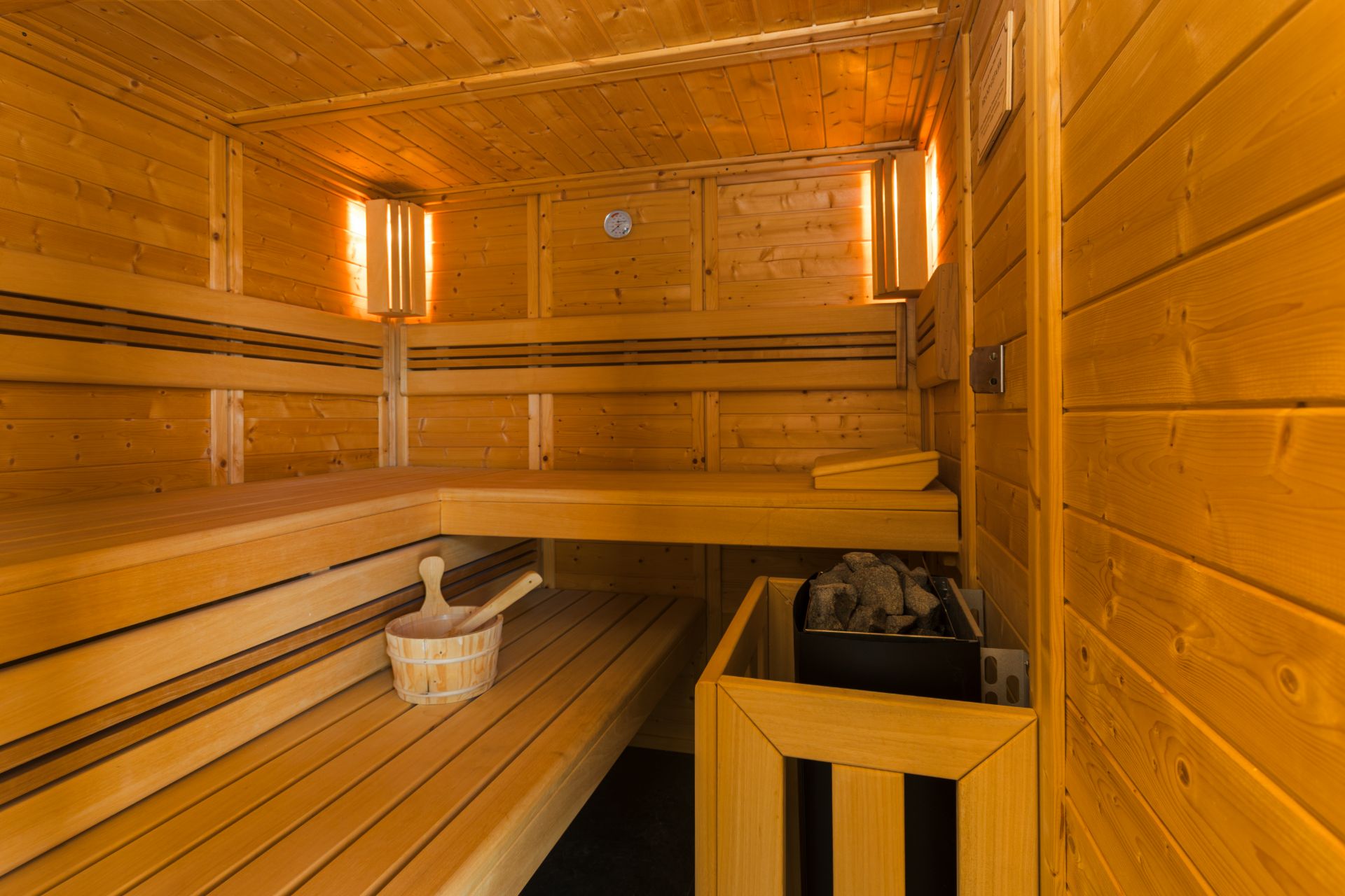 Innenansicht einer privaten Sauna mit Holzbänken und Saunaofen.