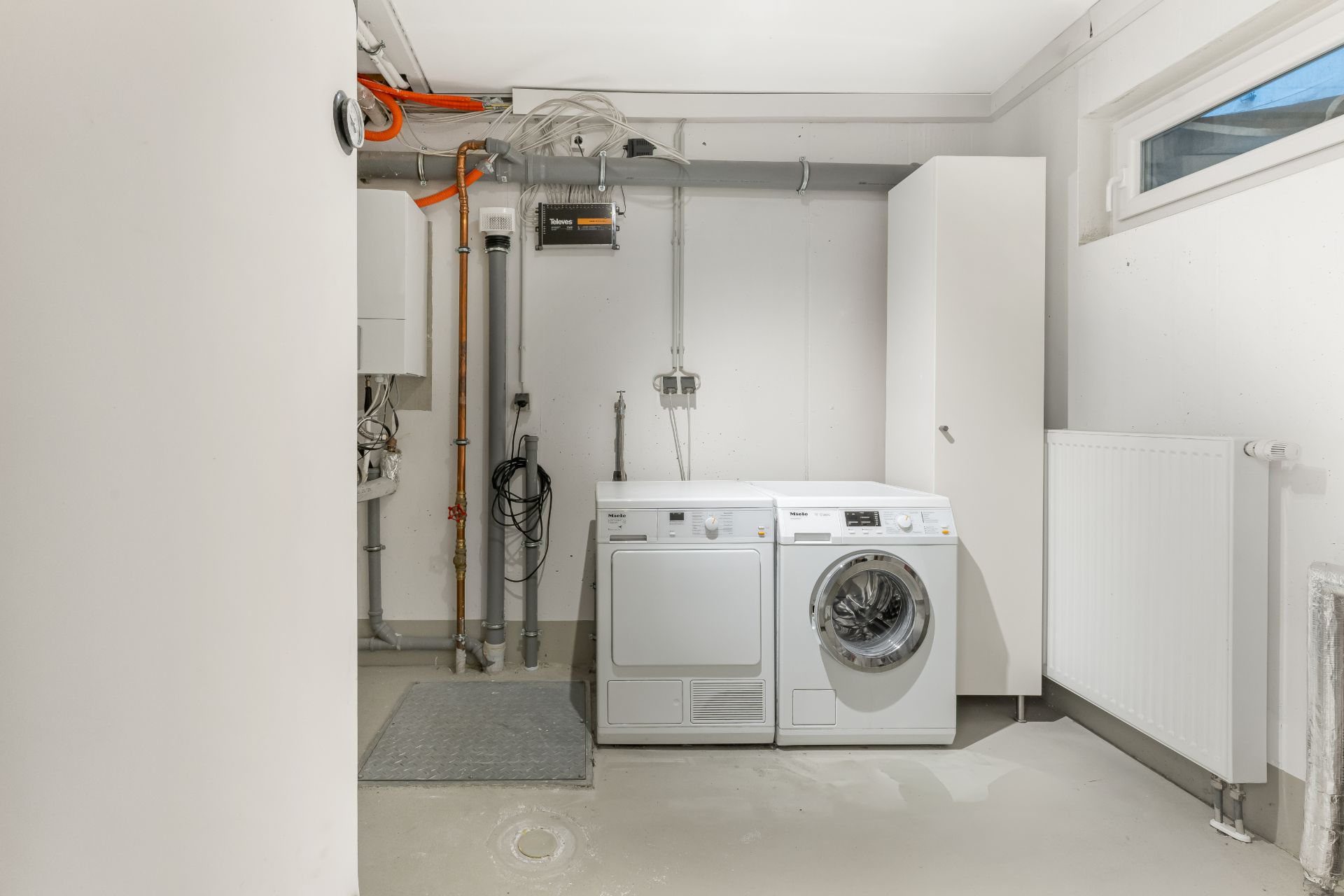 Hauswirtschaftsraum mit Waschmaschine und Trockner neben einem weißen Schrank.