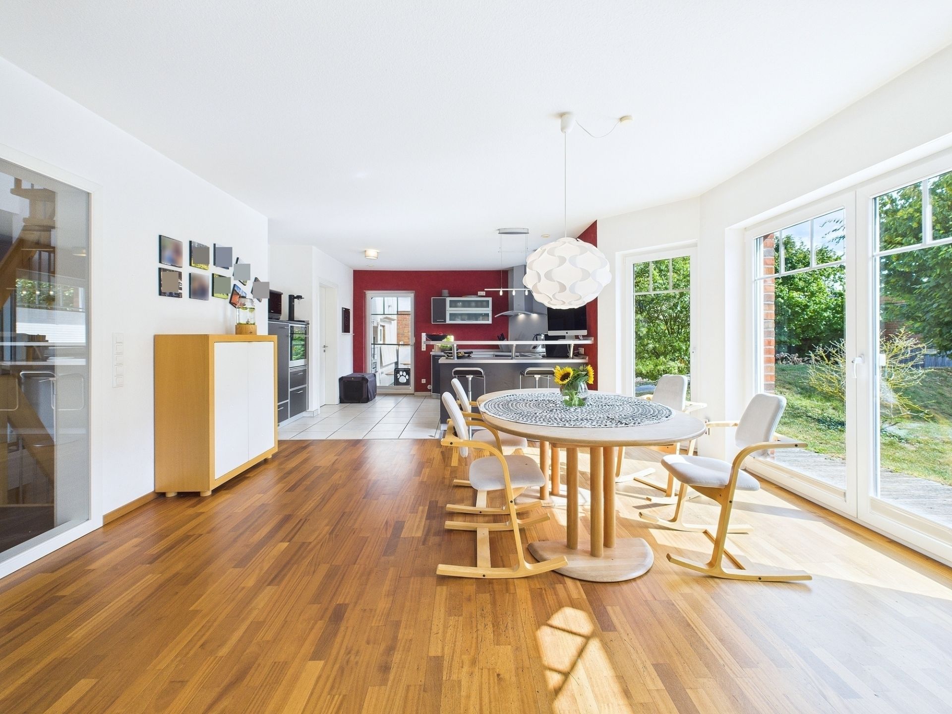 Heller Essbereich mit rundem Holztisch, vier Stühlen und Zugang zur offenen Küche und Terrasse.