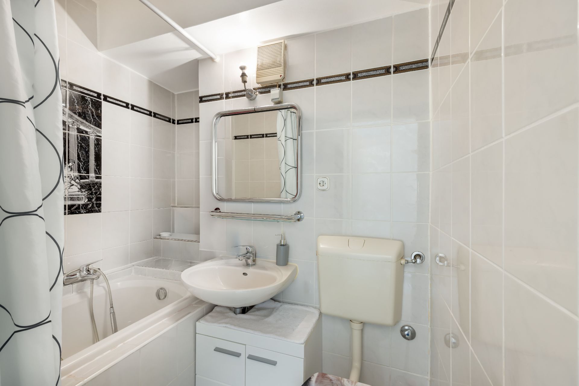 Kleines Badezimmer mit Badewanne, Waschbecken, Spiegel und Toilette.
