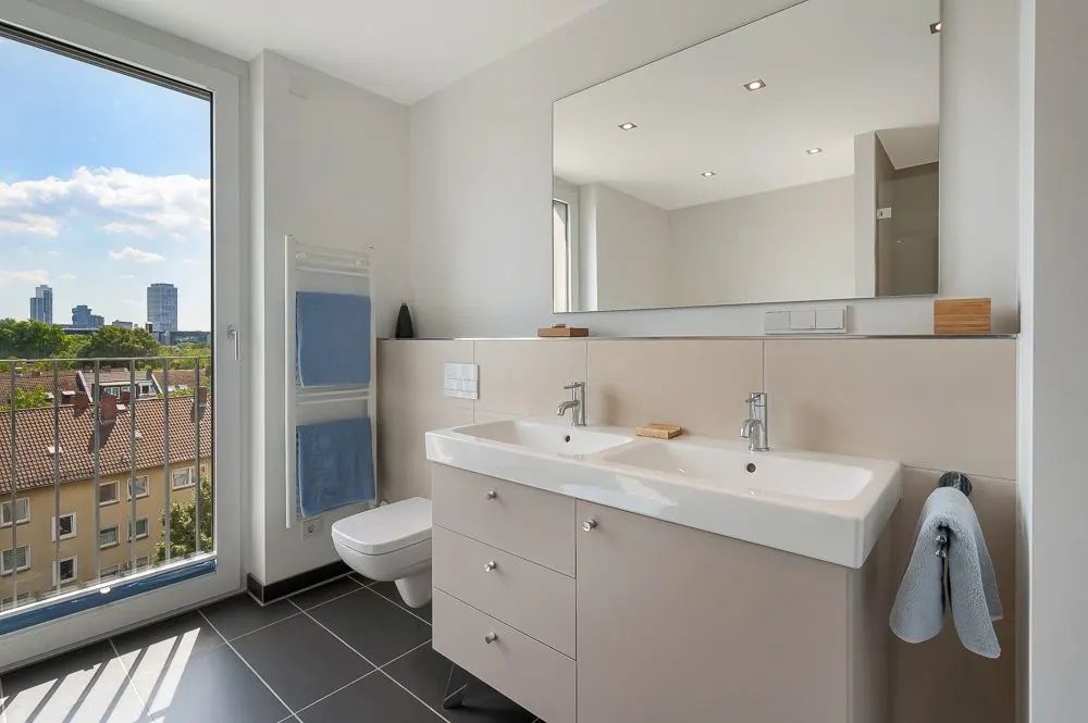 Modernes Badezimmer mit Doppelwaschbecken, großem Spiegel und Fenster mit Stadtblick.