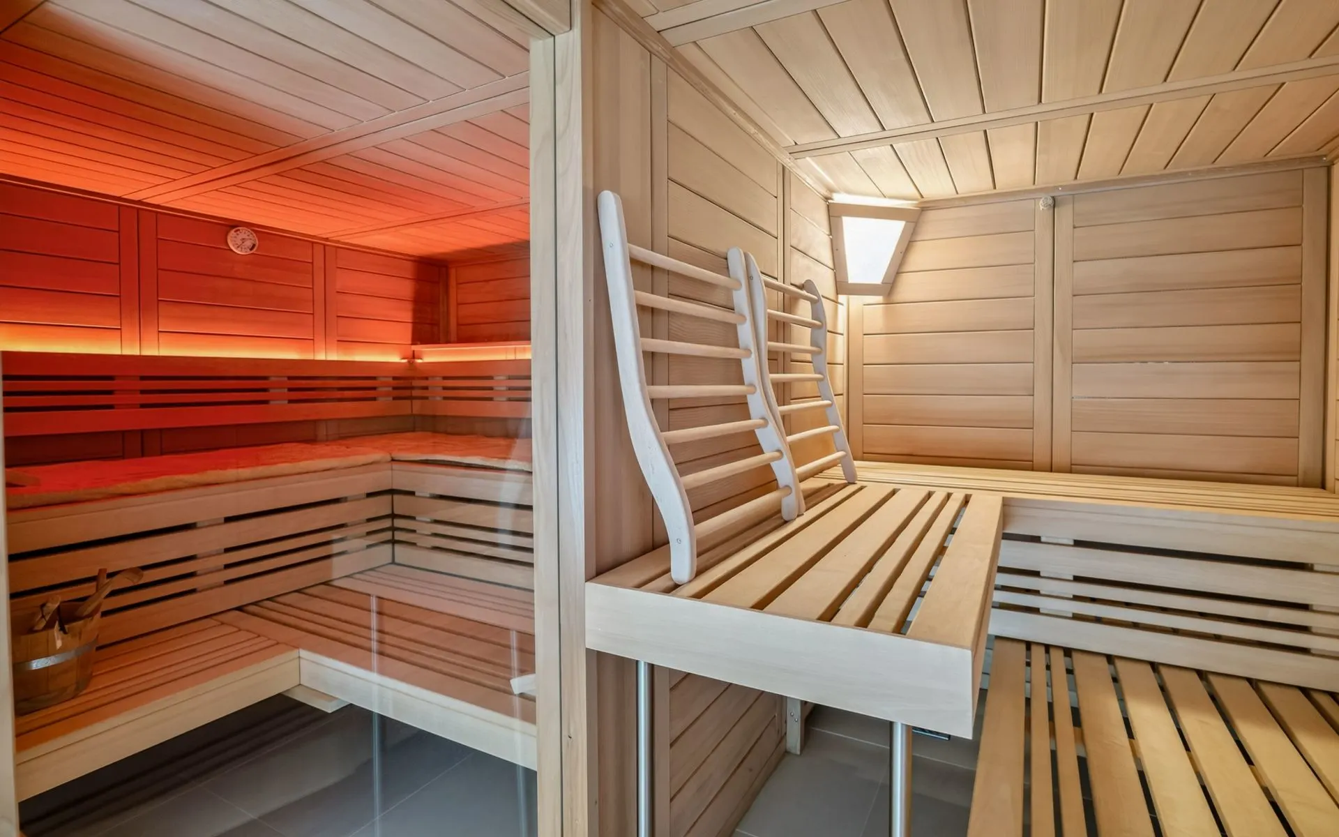Moderne Sauna mit Holzverkleidung, Holzbänken und indirekter Beleuchtung.