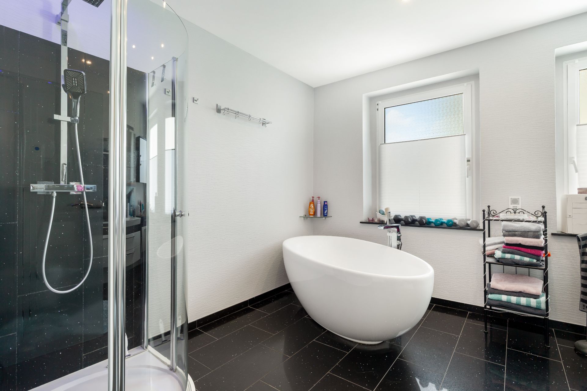 Modernes Badezimmer mit freistehender Badewanne, Dusche und Handtuchregal.