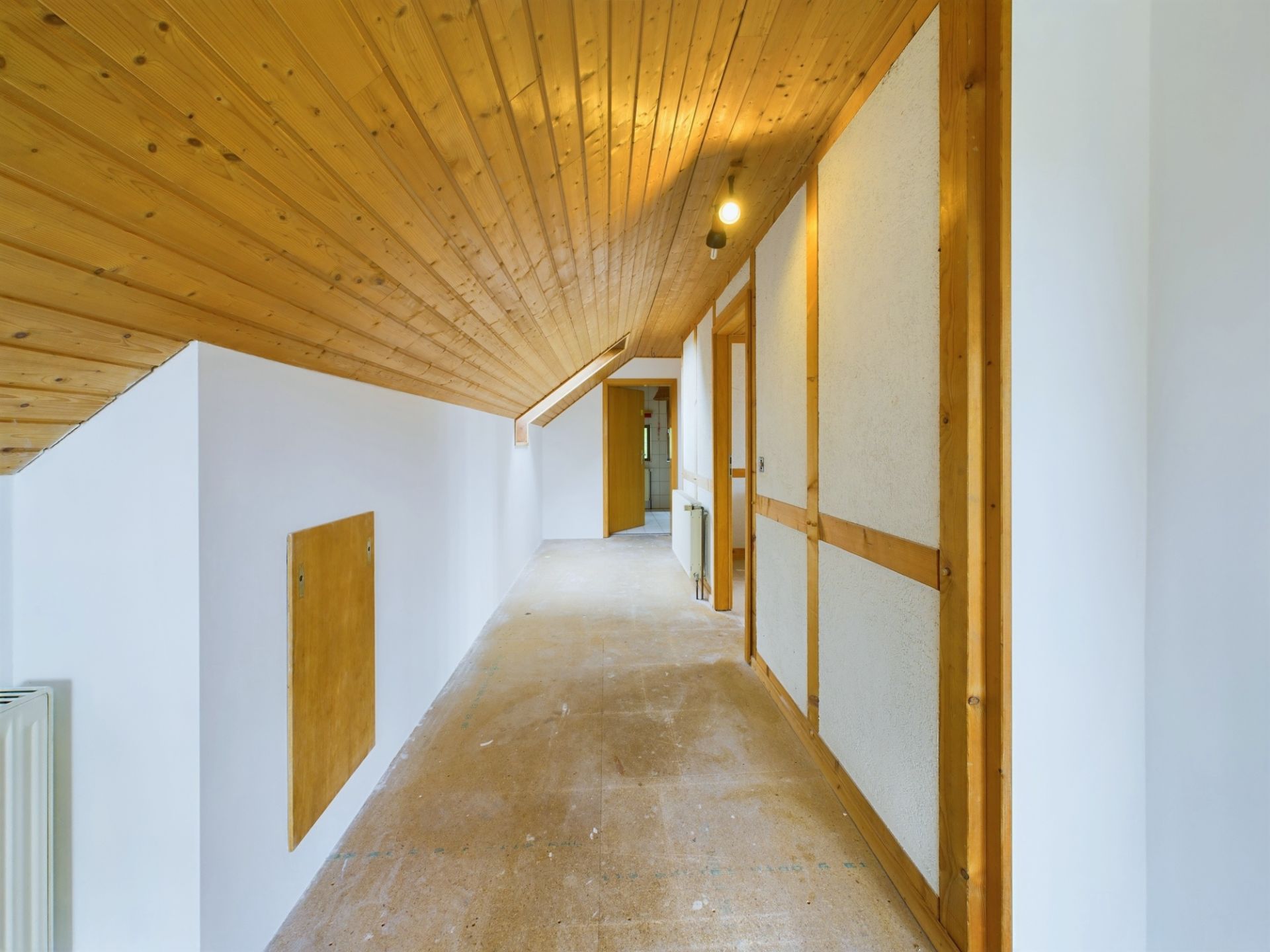 Heller Flur mit Holzdecke, weißen Wänden und mehreren Türen in einem Wohnhaus.