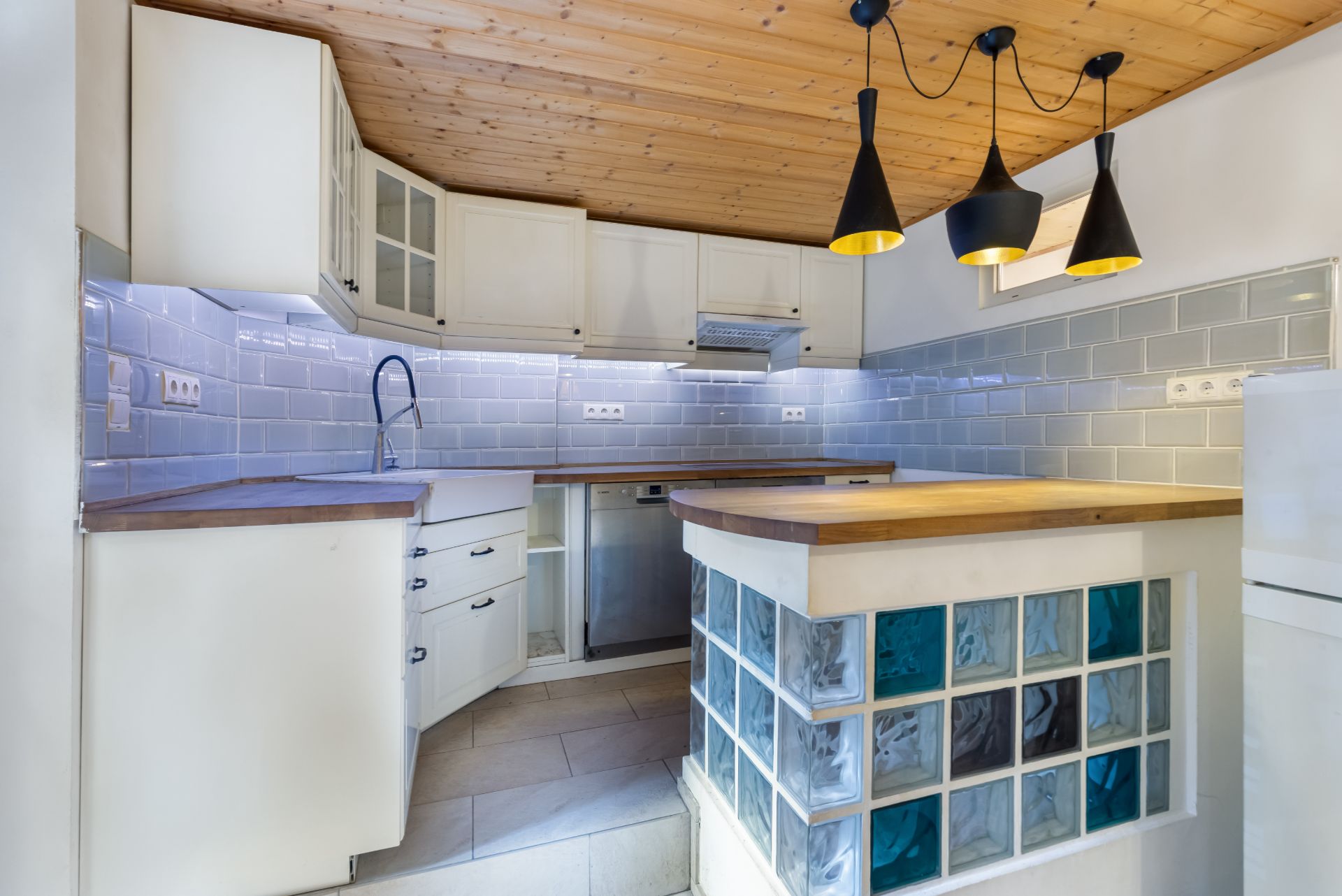 Moderne Küche mit weißen Schränken, Holzdecke und Glasbausteinen an der Theke.