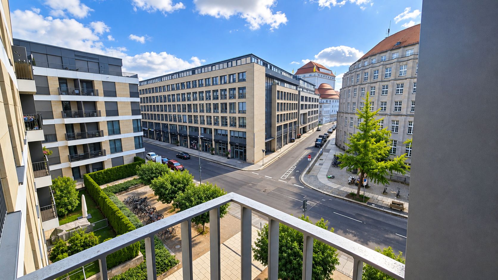 Blick von einem Balkon auf eine ruhige Straße mit modernen und historischen Gebäuden.
