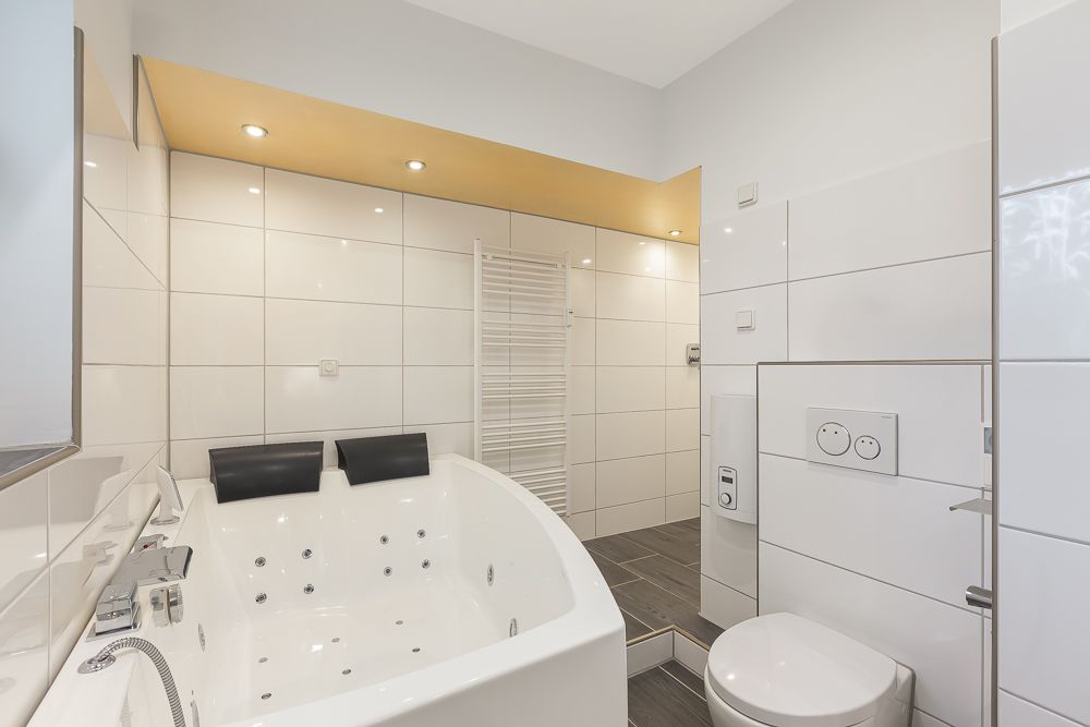 Modernes Badezimmer mit großer Eckbadewanne, Toilette und begehbarer Dusche.