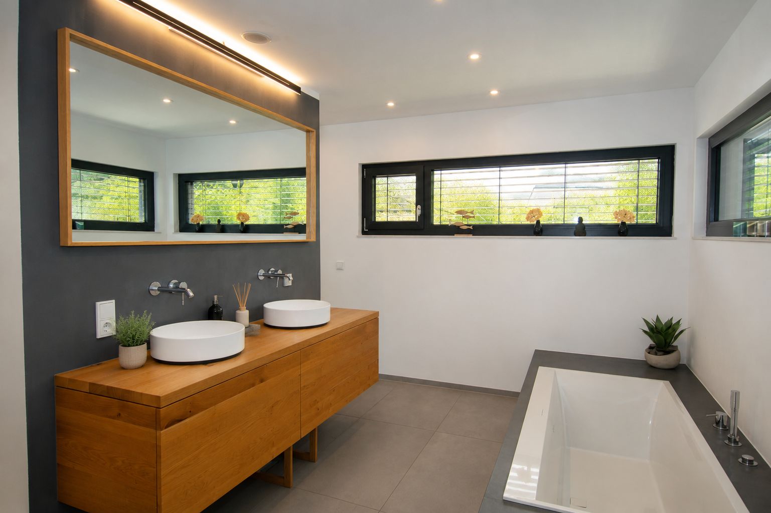 Modernes Badezimmer mit Holzwaschtisch, zwei Waschbecken, großer Spiegel und Badewanne.