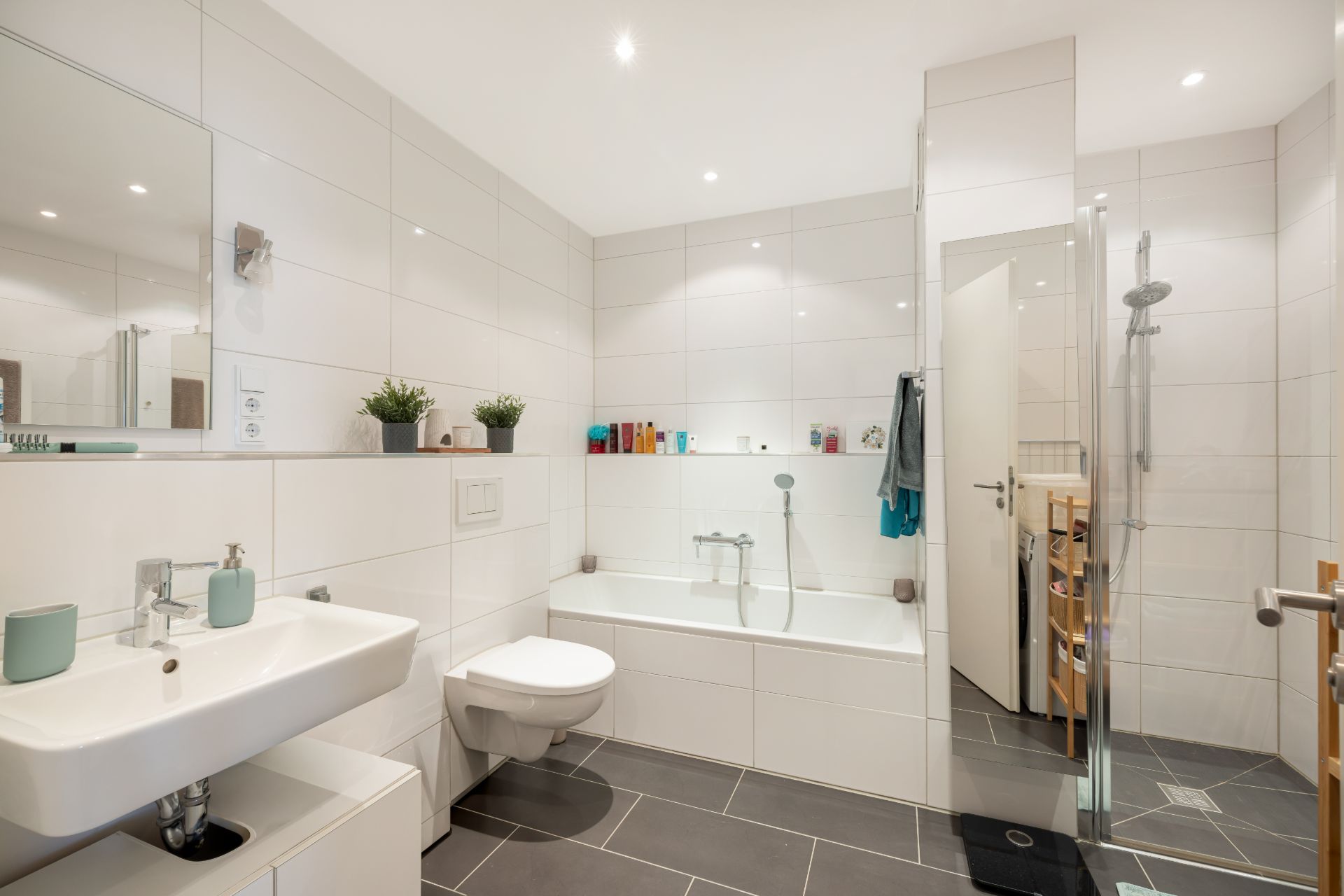 Modernes Badezimmer mit Badewanne, Dusche, Waschbecken und weißen Fliesen.