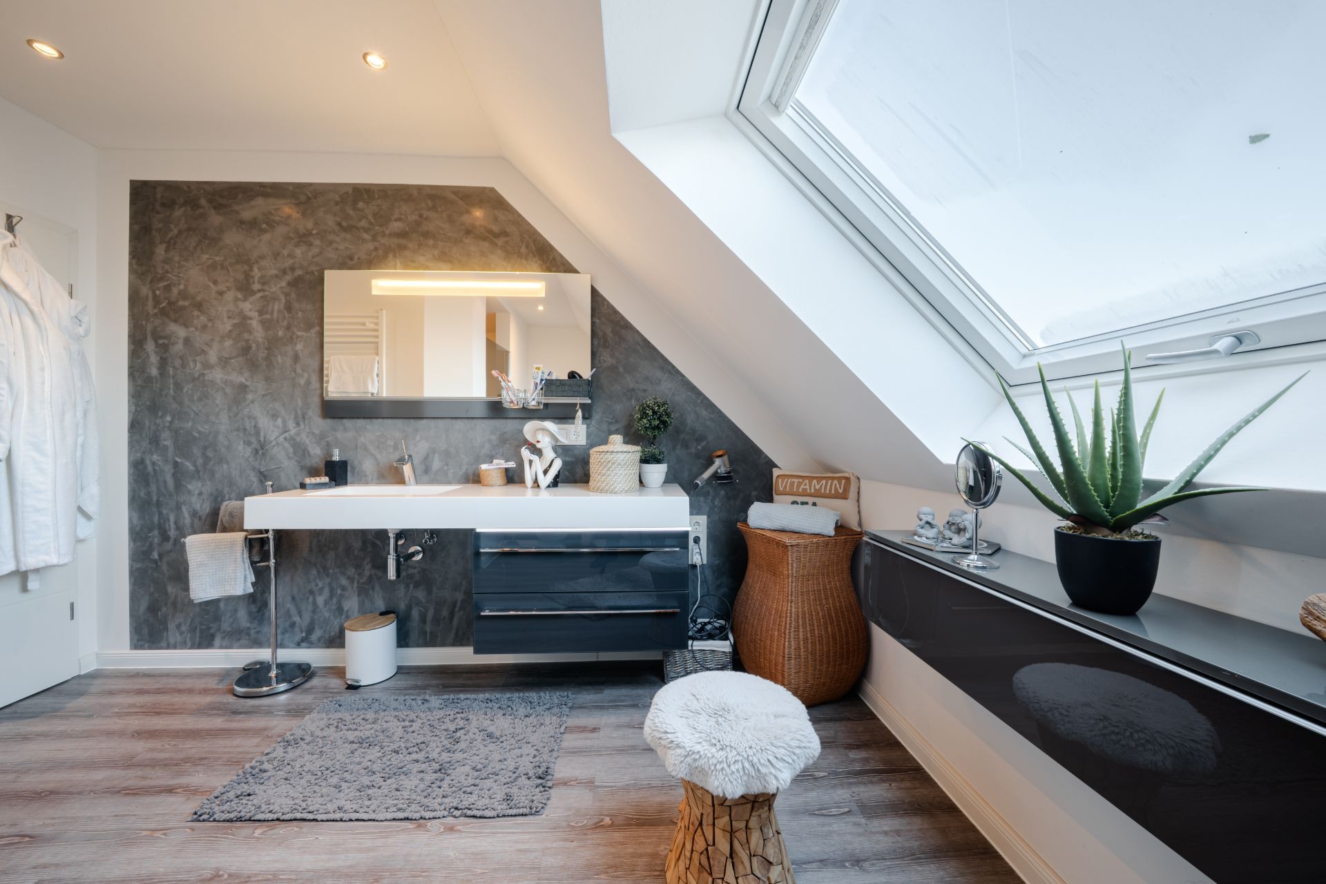 Modernes Badezimmer mit großem Dachfenster, Waschtisch, Spiegel und Dekopflanzen.