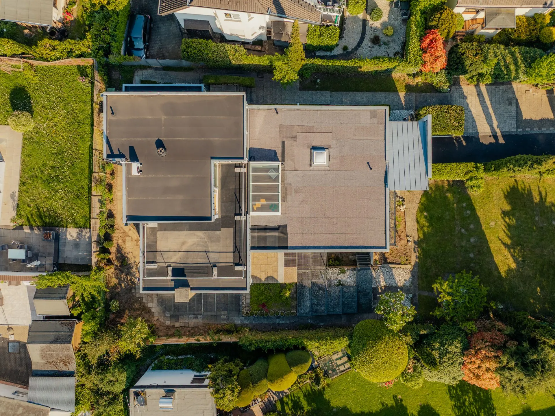 Luftaufnahme eines modernen Wohnhauses mit Flachdach und umliegendem Garten.
