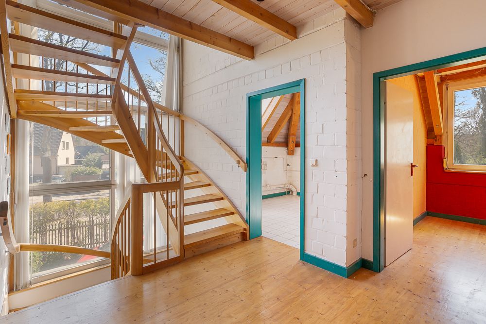 Heller Flur mit hölzerner Wendeltreppe, Sichtfenster und zwei angrenzenden Zimmern.