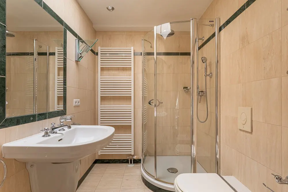 Modernes Badezimmer mit Dusche, Waschbecken, WC, Spiegel und Handtuchheizkörper.