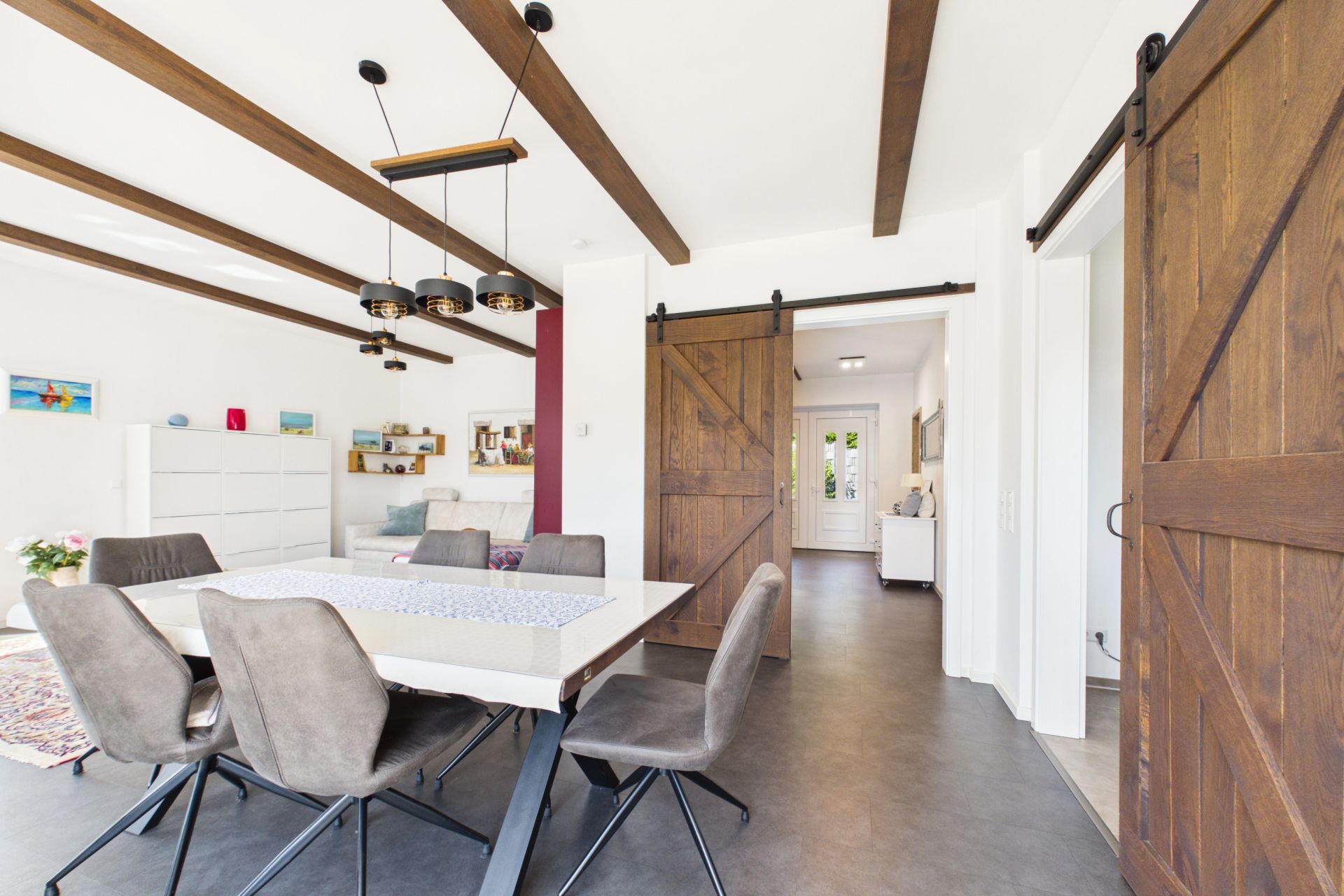 Helles Esszimmer mit modernen Stühlen, Holzbalken und Schiebetüren aus Holz.