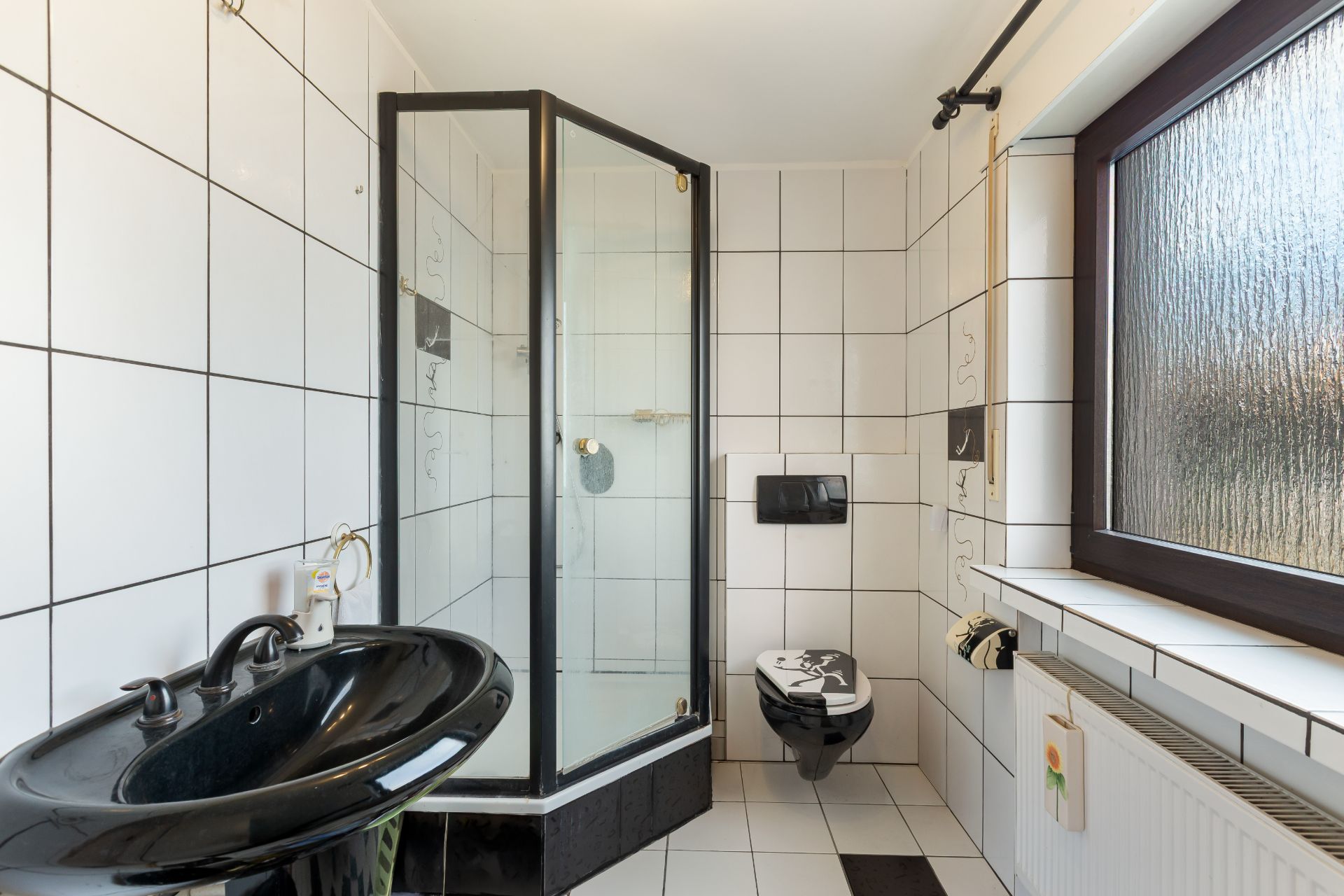 Badezimmer mit schwarzem Waschbecken, Dusche, Wandtoilette und großem Fenster.