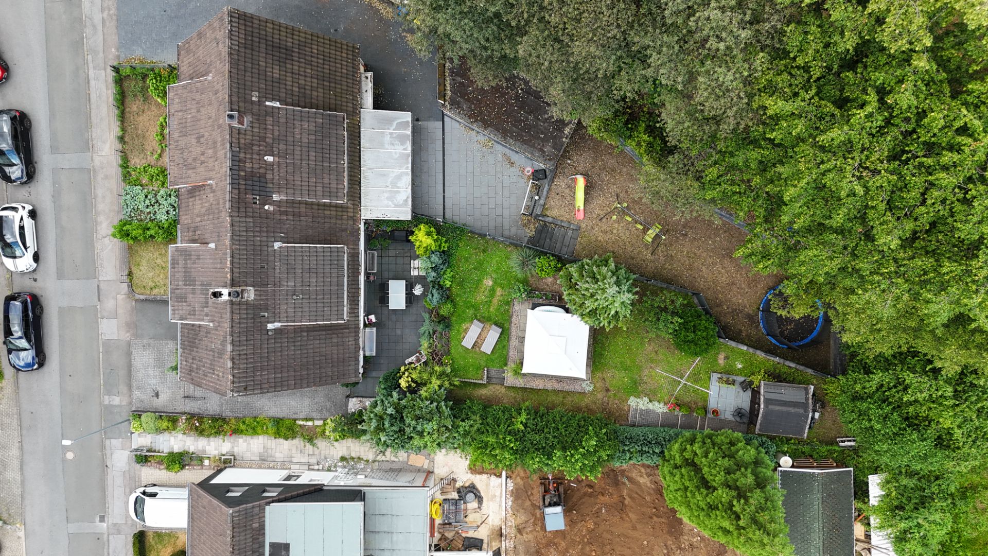 Luftaufnahme eines Wohnhauses mit Garten, Terrasse und umgebenden Bäumen.