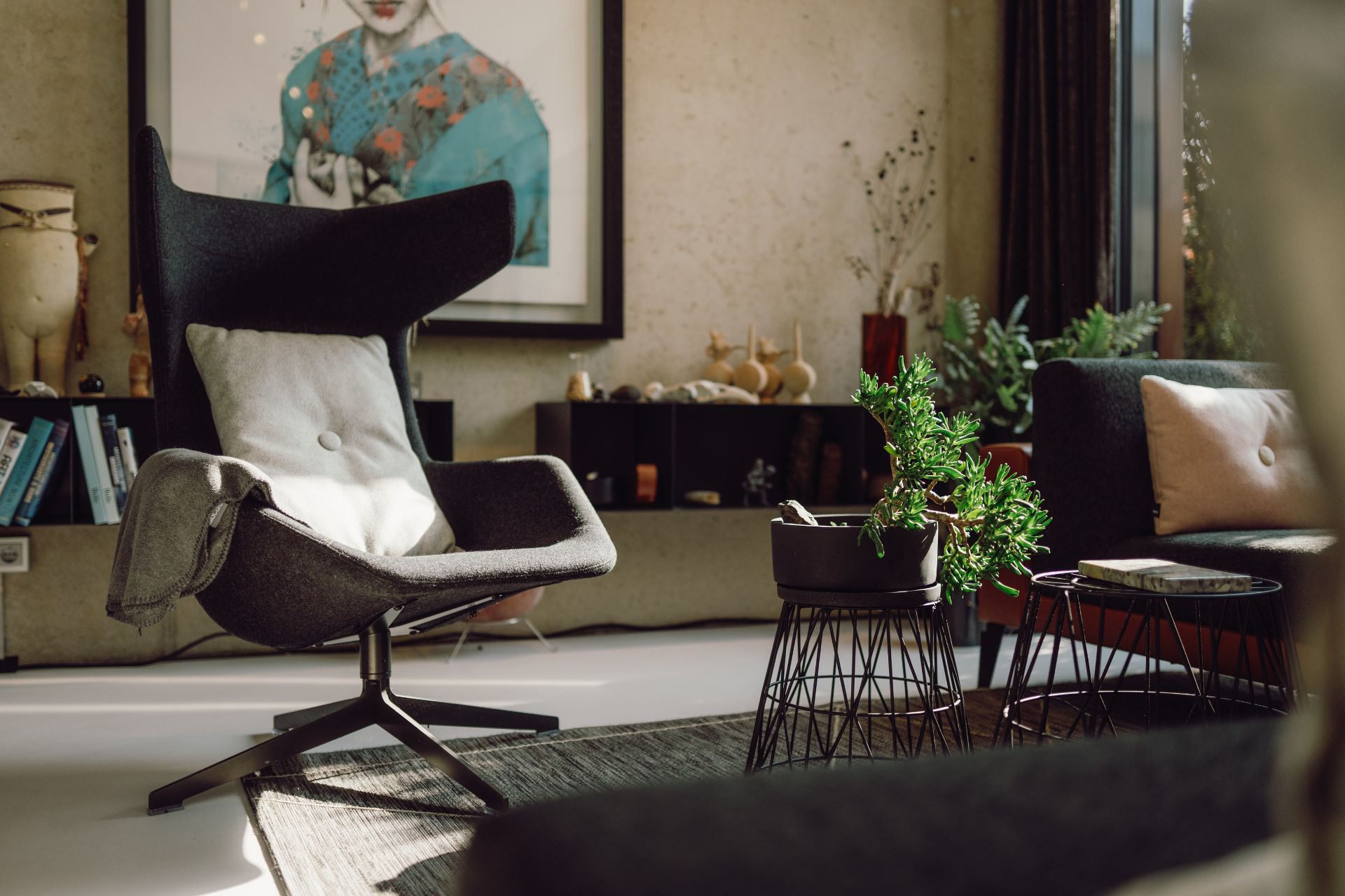 Modernes Wohnzimmer mit Sessel, Sofas, Zimmerpflanze und großem Wandbild.