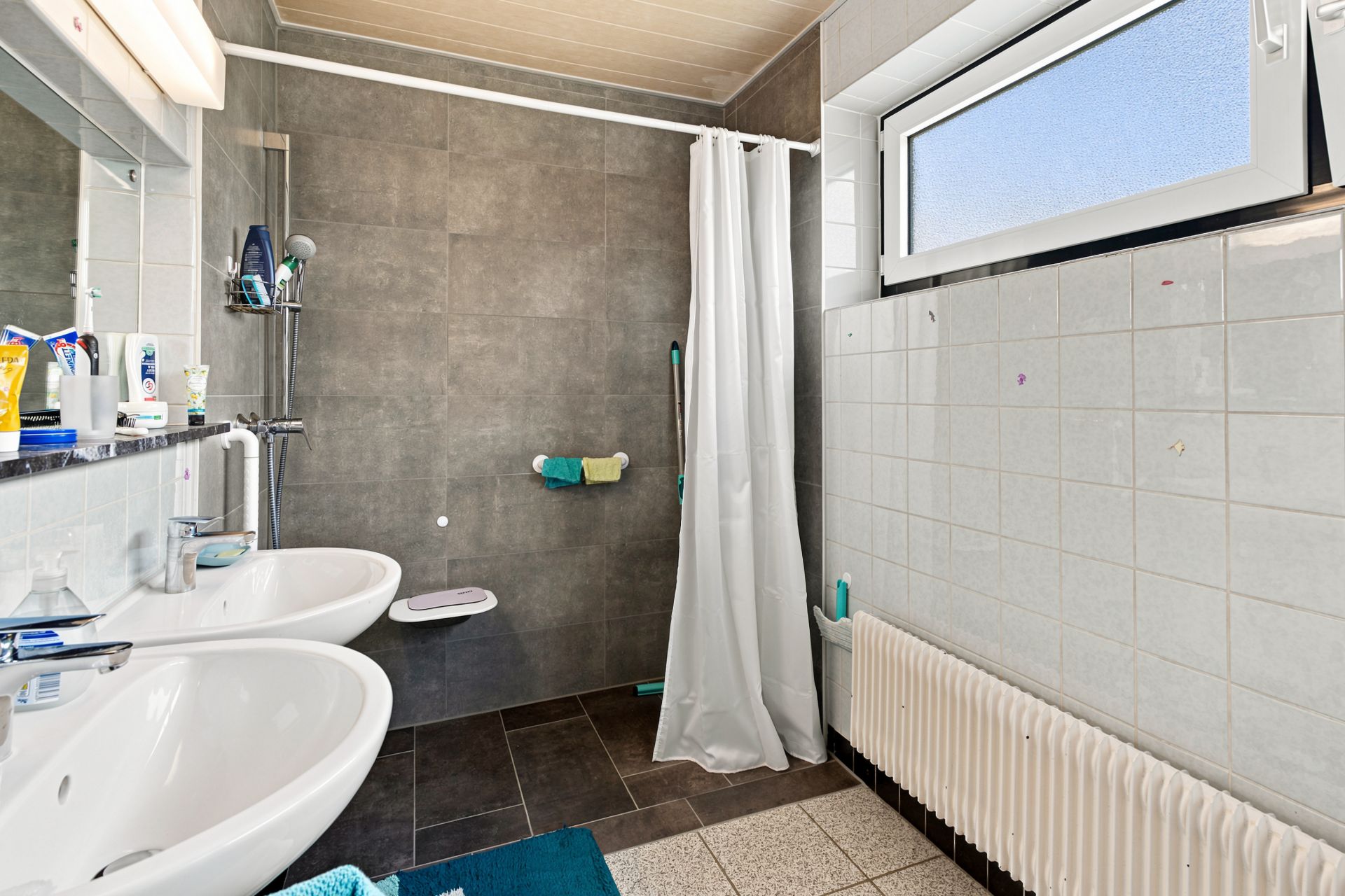 Modernes Badezimmer mit zwei Waschbecken, Dusche mit Vorhang und Fenster.