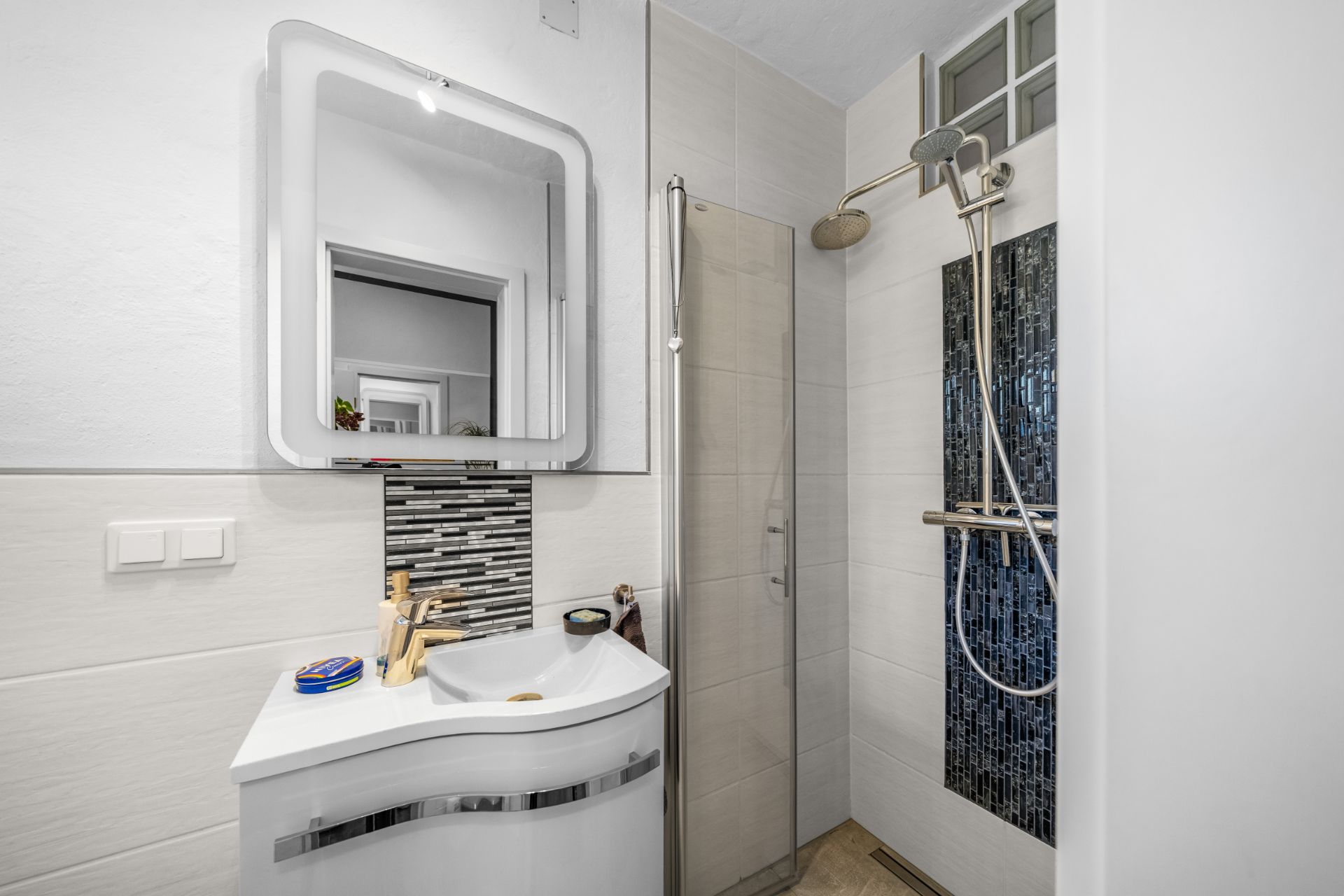 Modernes kleines Badezimmer mit Dusche, Waschbecken und Spiegel.