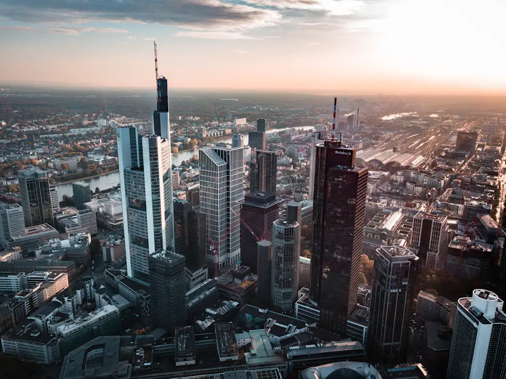 Blick auf eine Stadt mit vielen Hochhäusern und Fluss im Hintergrund bei Sonnenuntergang.
