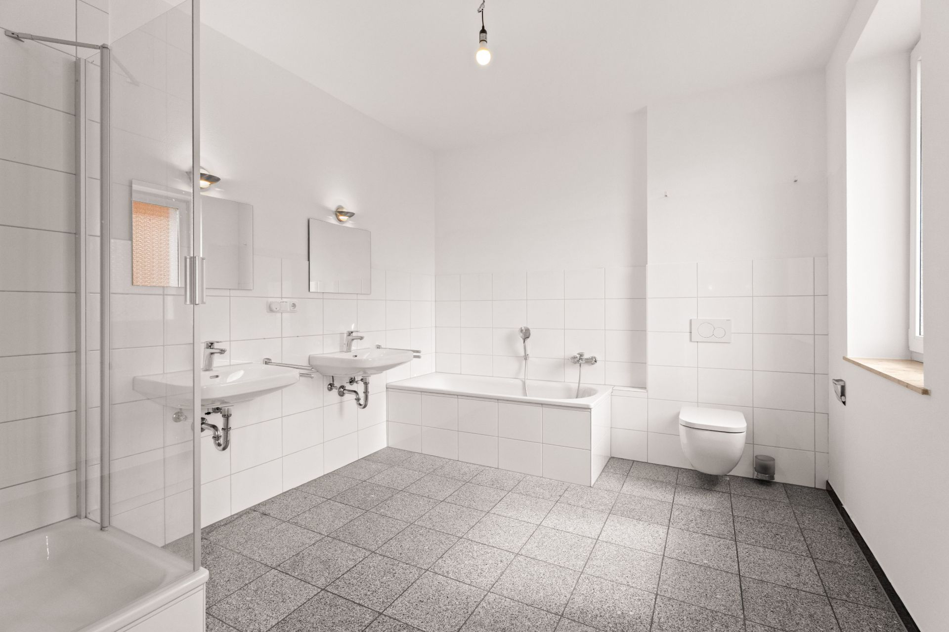 Modernes Badezimmer mit Badewanne, zwei Waschbecken, Dusche, WC und Fenster.