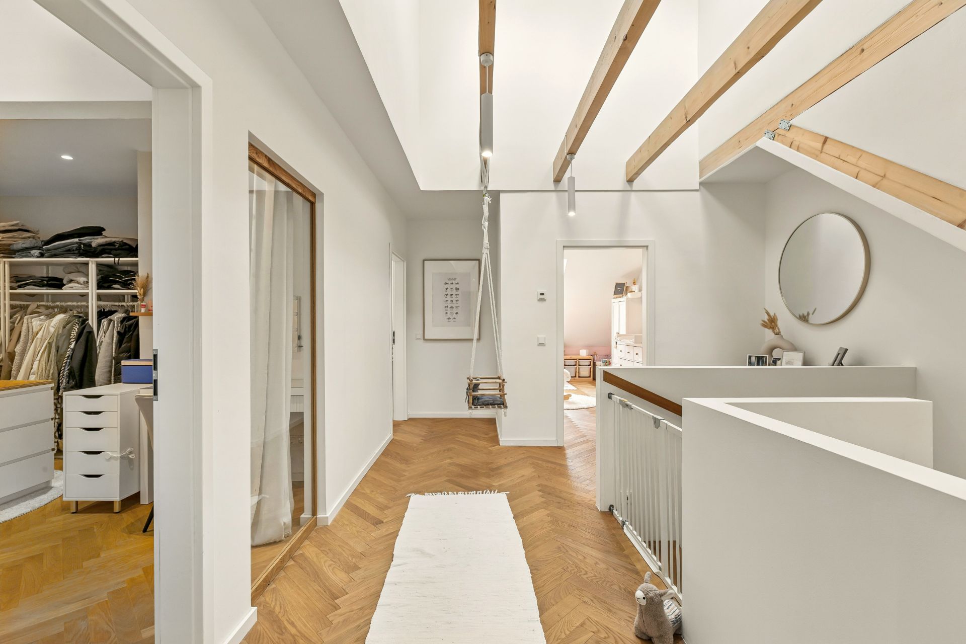 Heller Flur mit Holzdecke, Schaukel, Spiegel, Teppich und Zugang zu Ankleideraum sowie weiterem Zimmer.