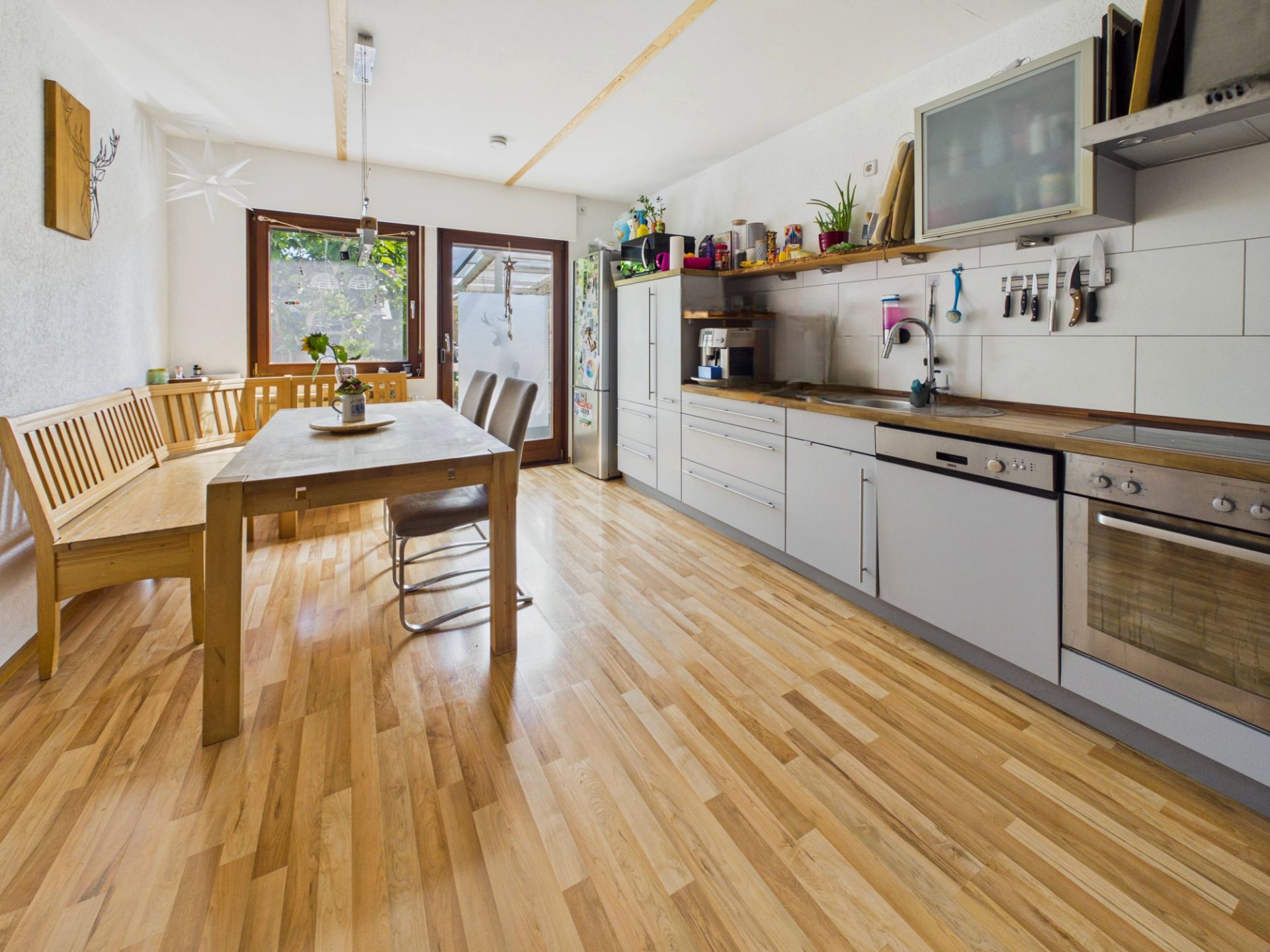 Helle Küche mit Holzboden, Essbereich, Eckbank und moderner Einbauküche.