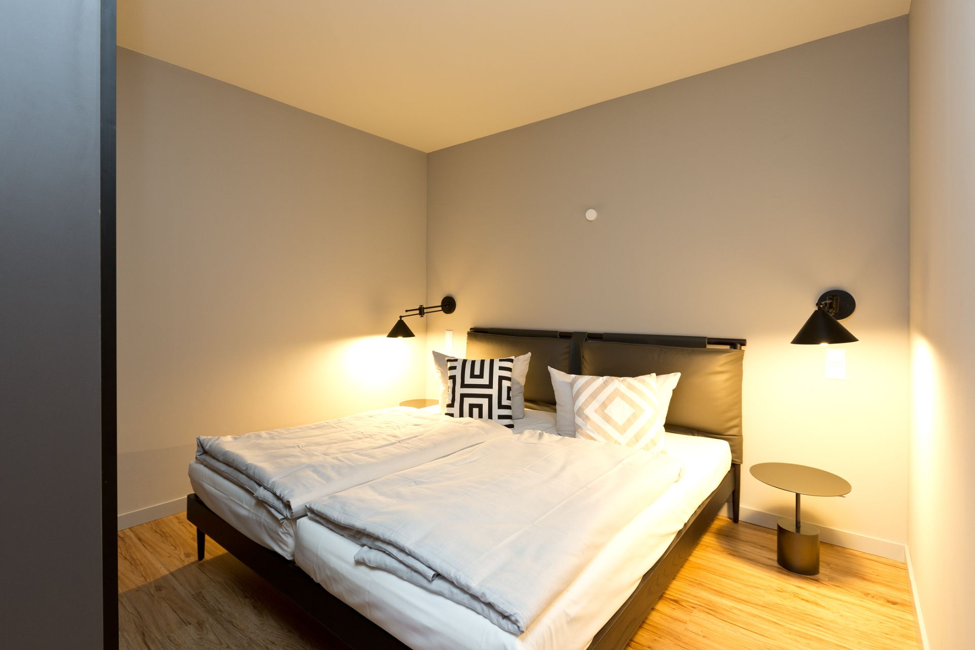 Schlafzimmer mit Doppelbett, zwei Nachttischen und schlichten Wandlampen.