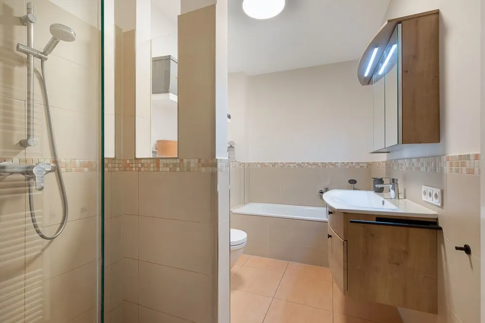 Modernes Badezimmer mit Dusche, Badewanne, Waschbecken und Spiegelschrank.