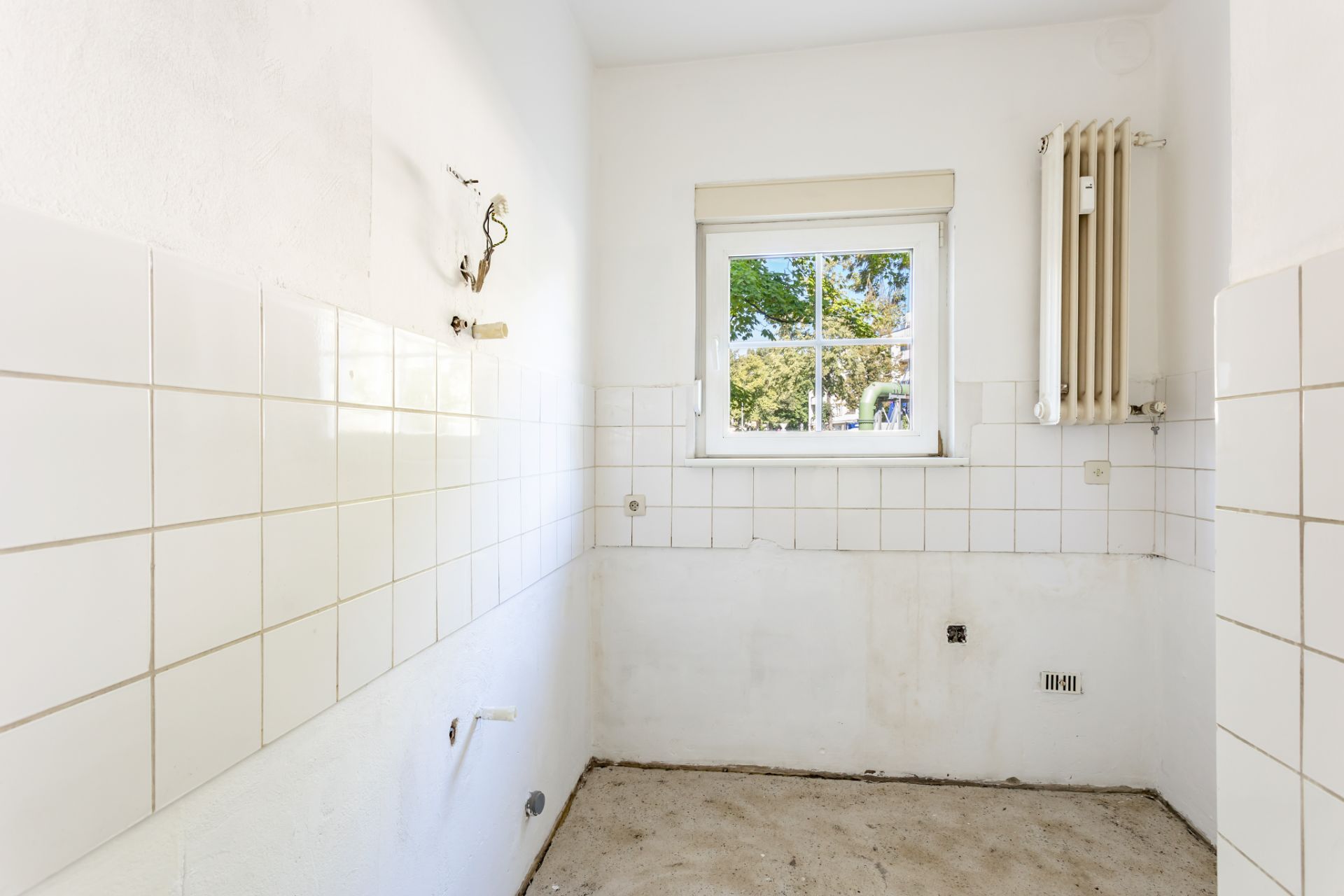 Leerer, gefliester Raum mit Fenster und Heizkörper, keine Möbel oder Geräte.