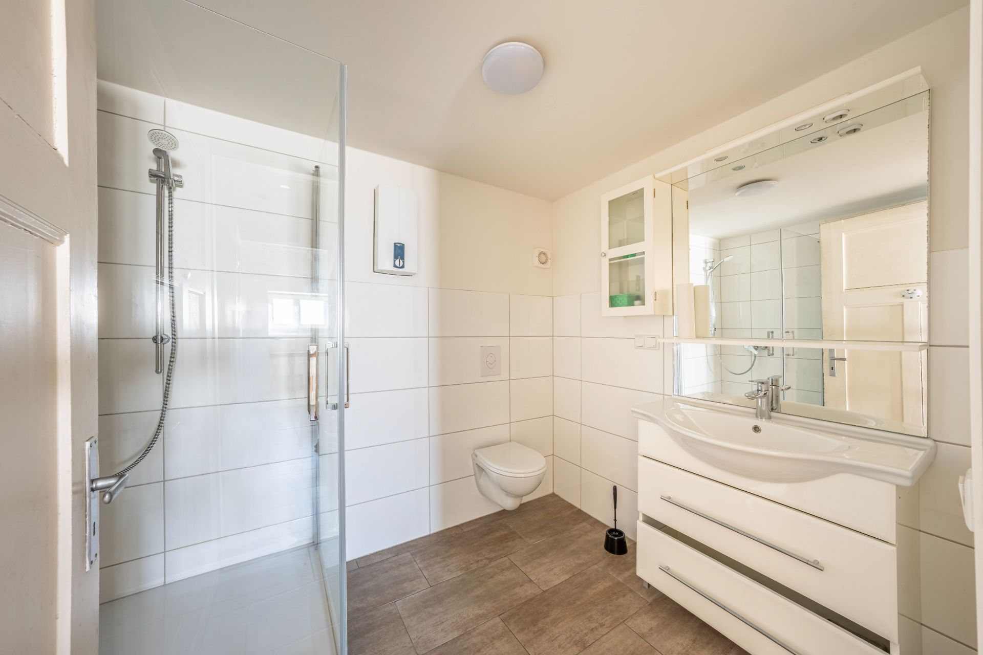 Modernes Badezimmer mit Dusche, WC, Waschbecken und großem Spiegel.