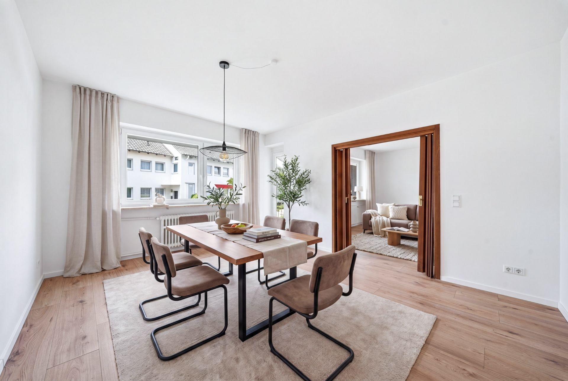 Heller Essbereich mit Holztisch, vier Stühlen und Blick ins Wohnzimmer.