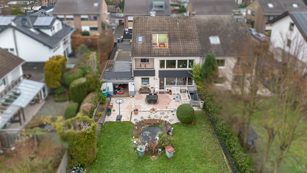 Blick auf ein Haus mit Terrasse, Garten, Rasenfläche und kleinem Teich.