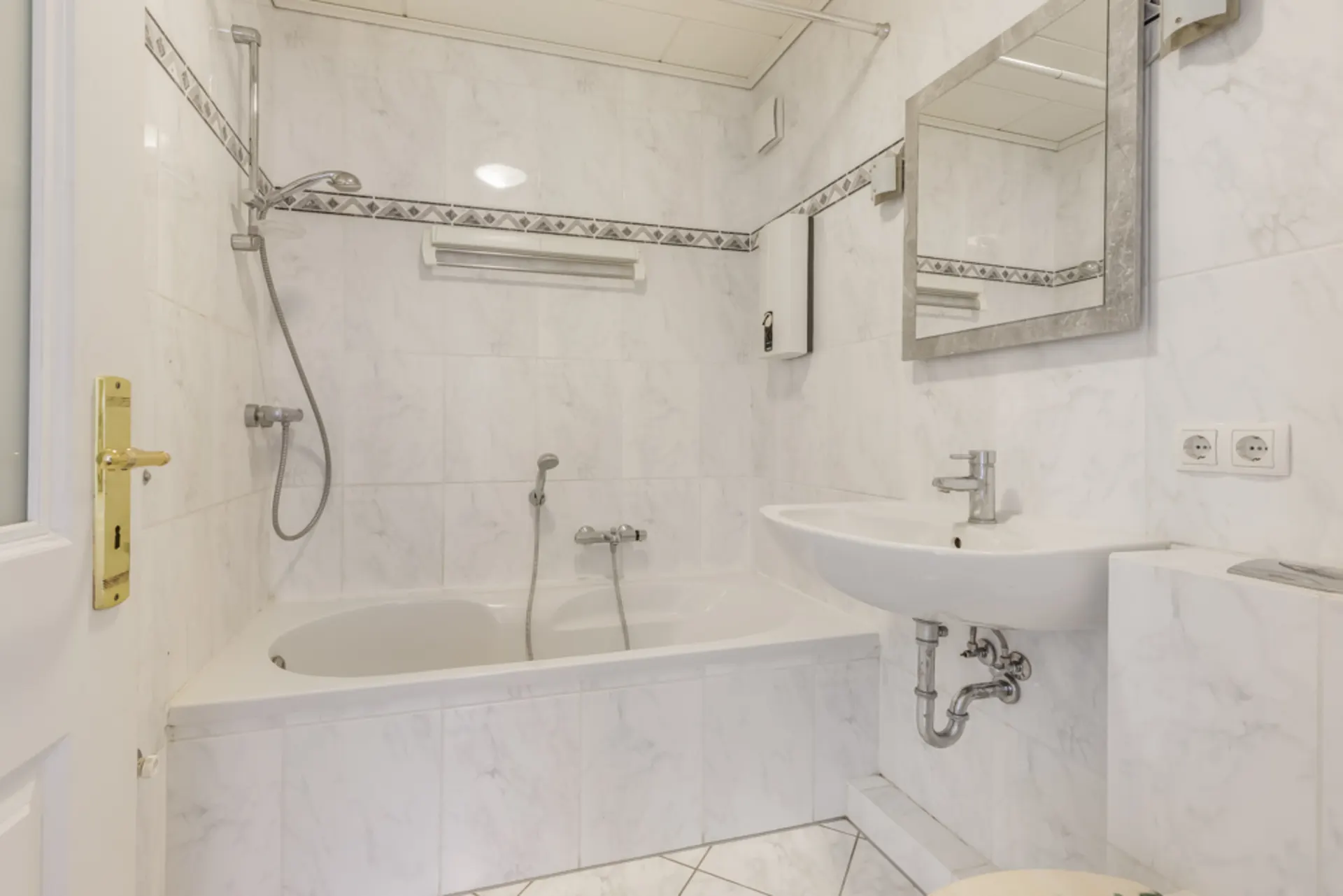 Helles Badezimmer mit Badewanne, Dusche, Waschbecken, Spiegel und weißen Fliesen.