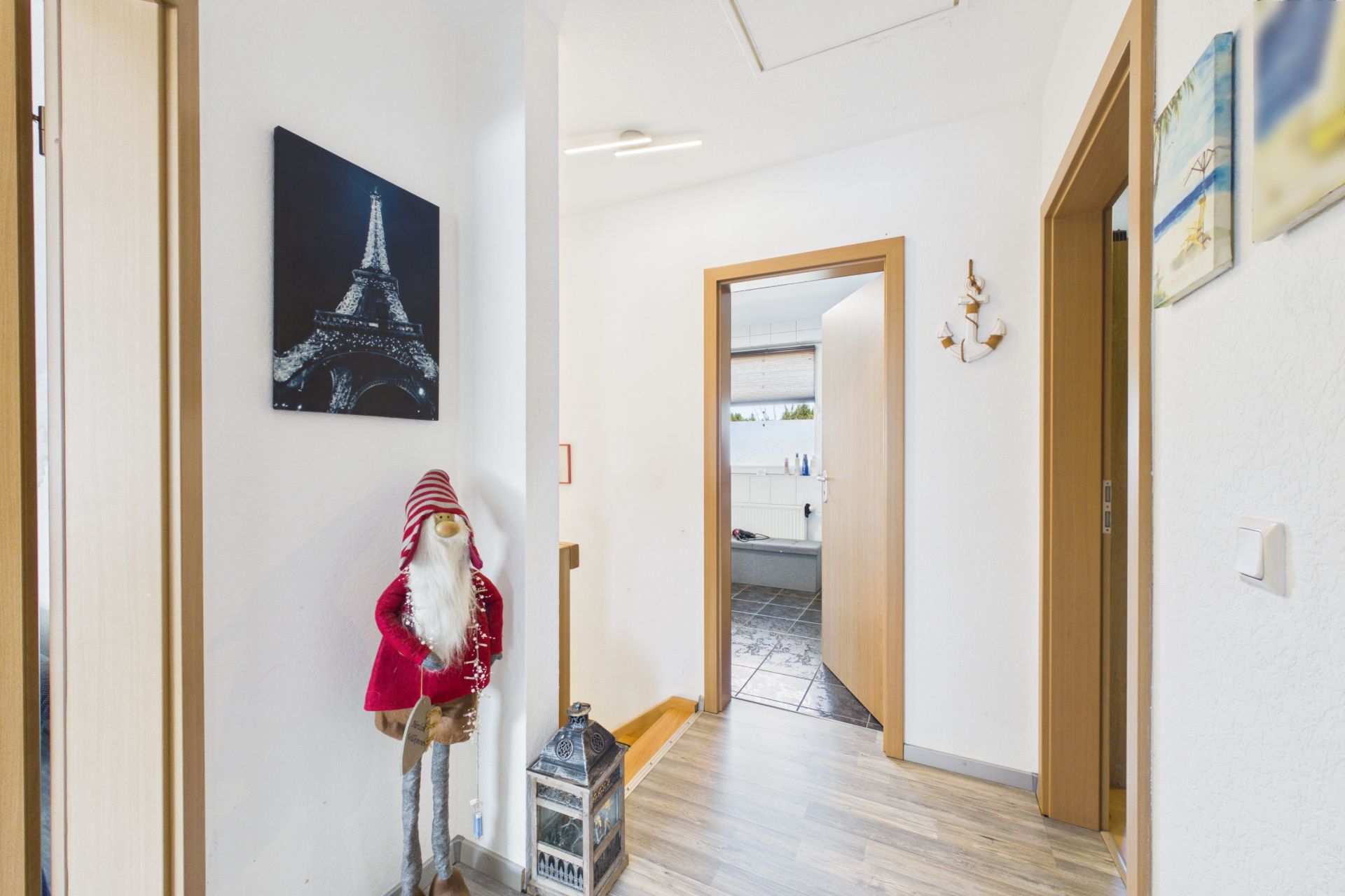 Heller Flur mit Holzfußboden, Wandbildern und Weihnachtsdekoration.