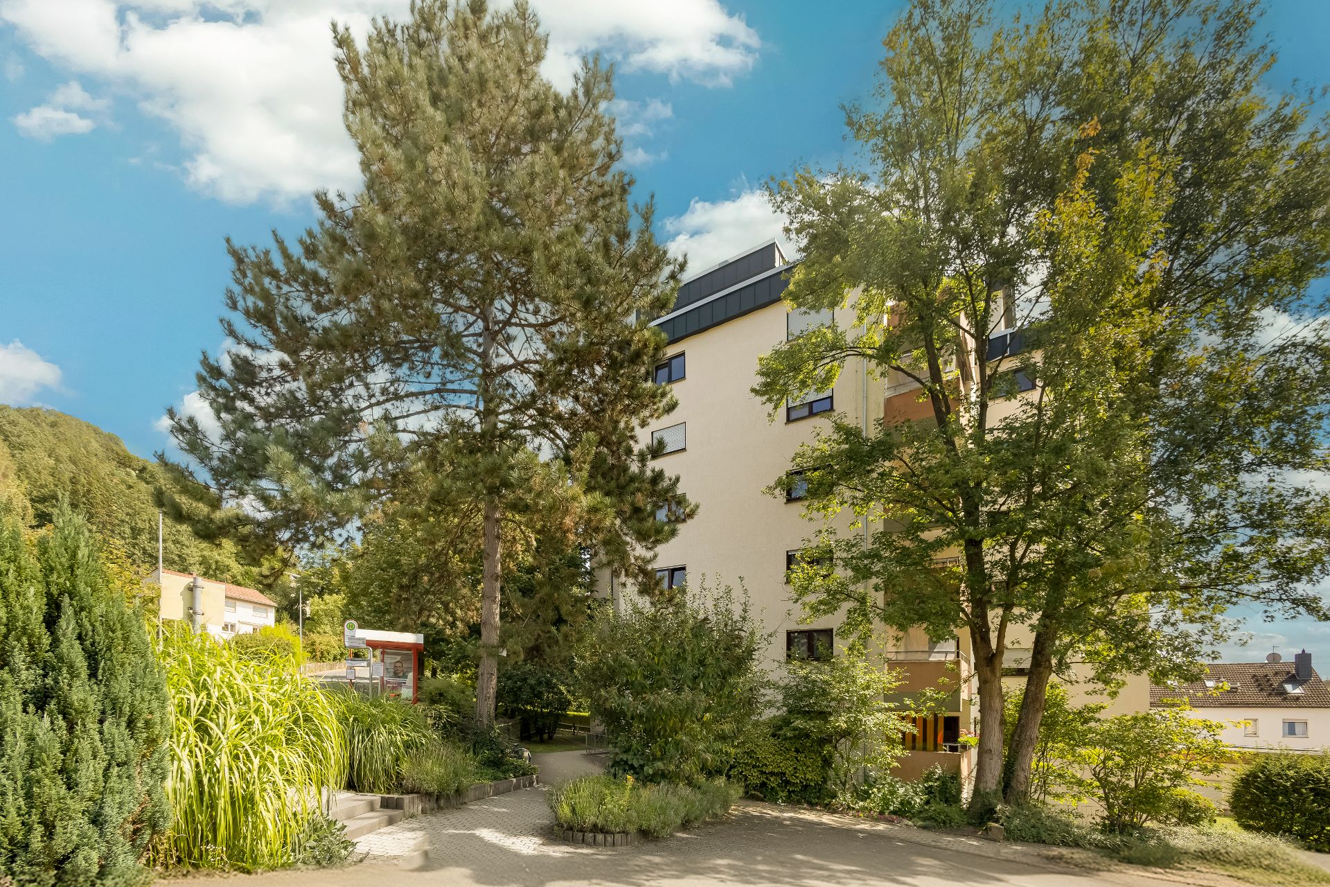 Mehrfamilienhaus mit mehreren Stockwerken, umgeben von Bäumen und Grünanlagen.