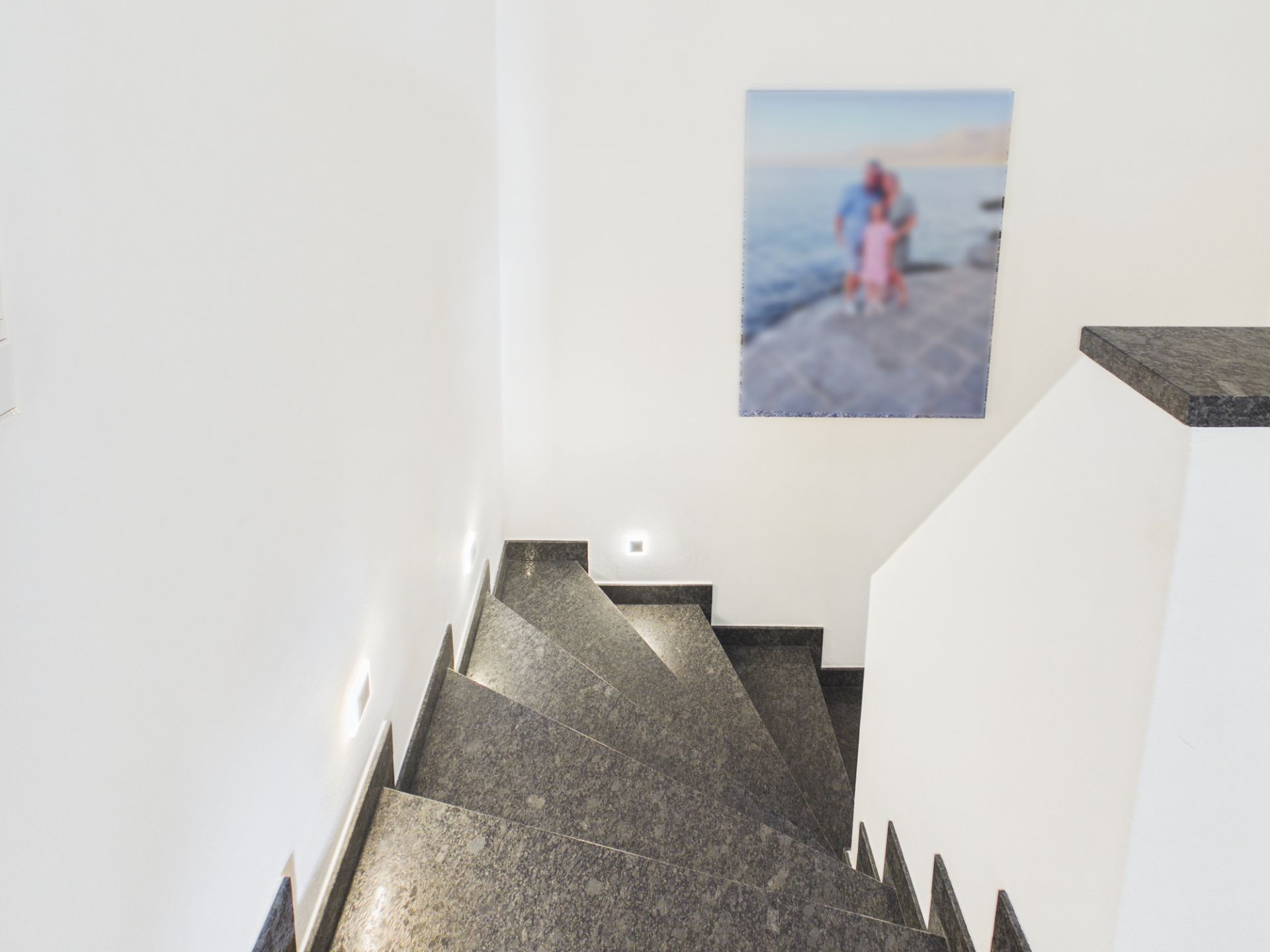 Dunkle Steintreppe mit weißen Wänden und einem großen Foto an der Wand.