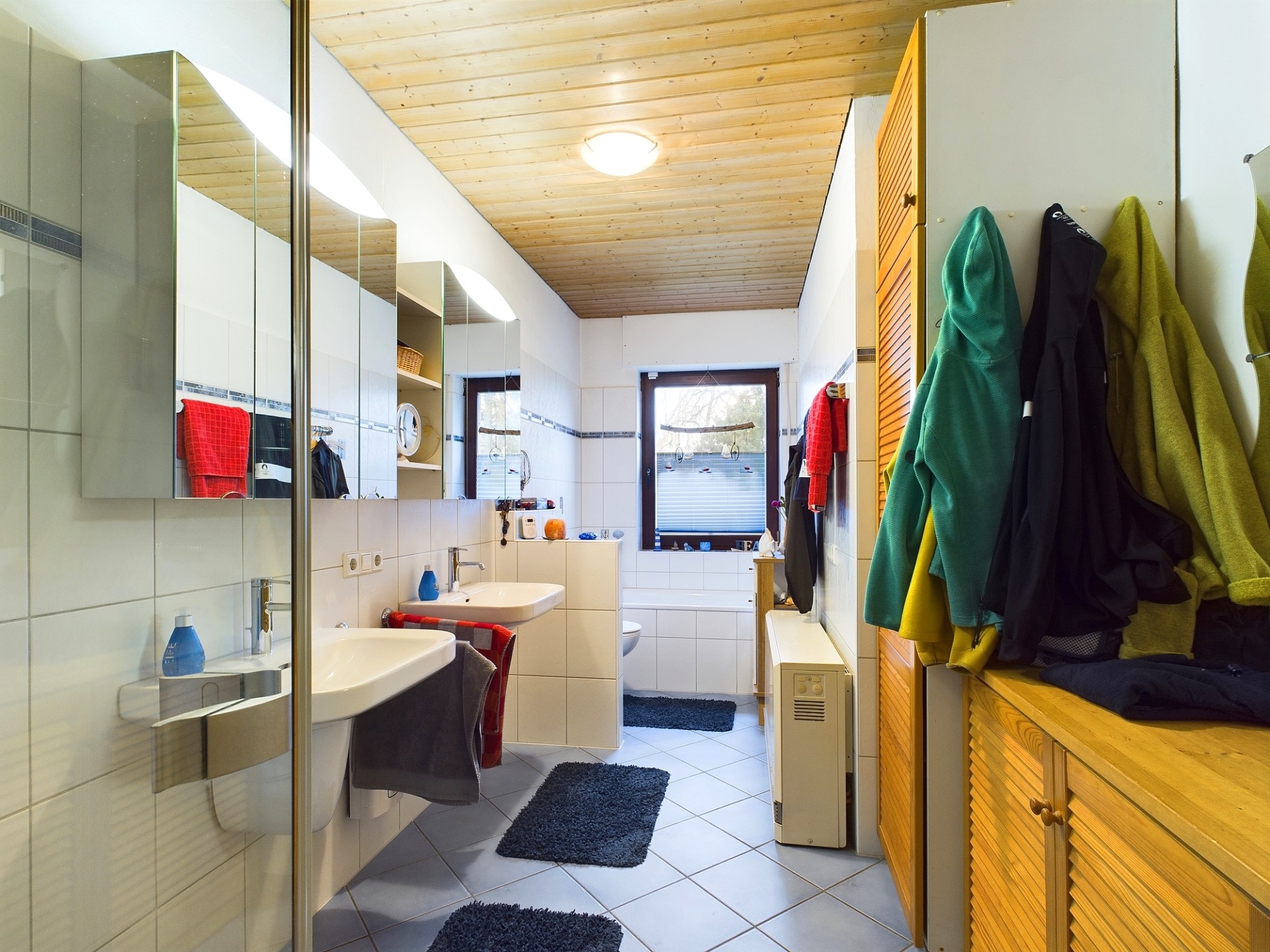 Modernes Badezimmer mit zwei Waschbecken, Spiegeln, Handtüchern und Fenstern.