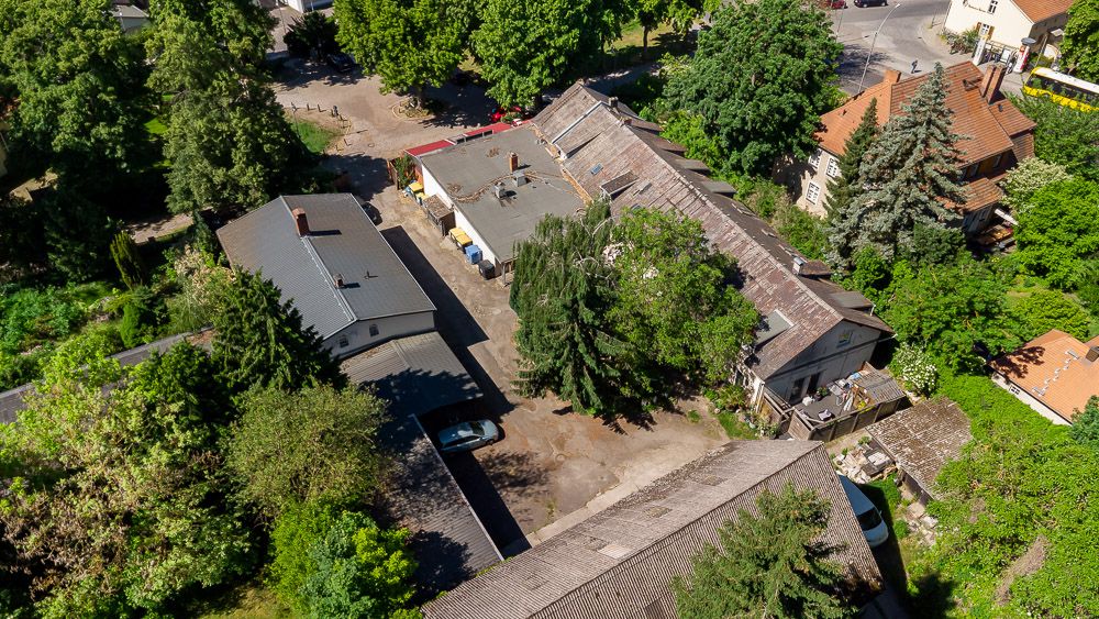 Luftaufnahme mehrerer Wohngebäude mit Innenhof und vielen Bäumen.