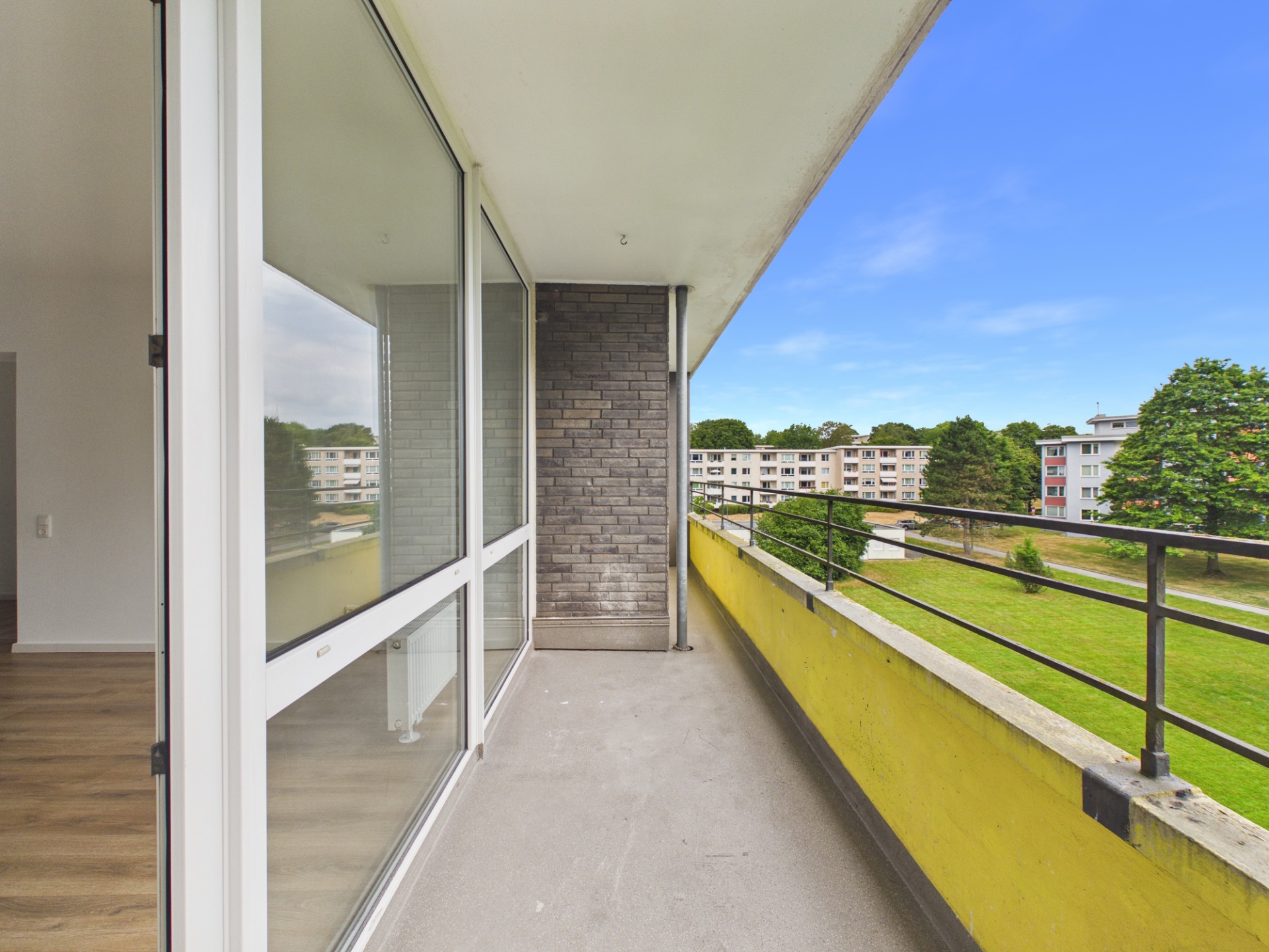 Balkon mit Geländer und Blick auf Wiese und benachbarte Wohnhäuser.