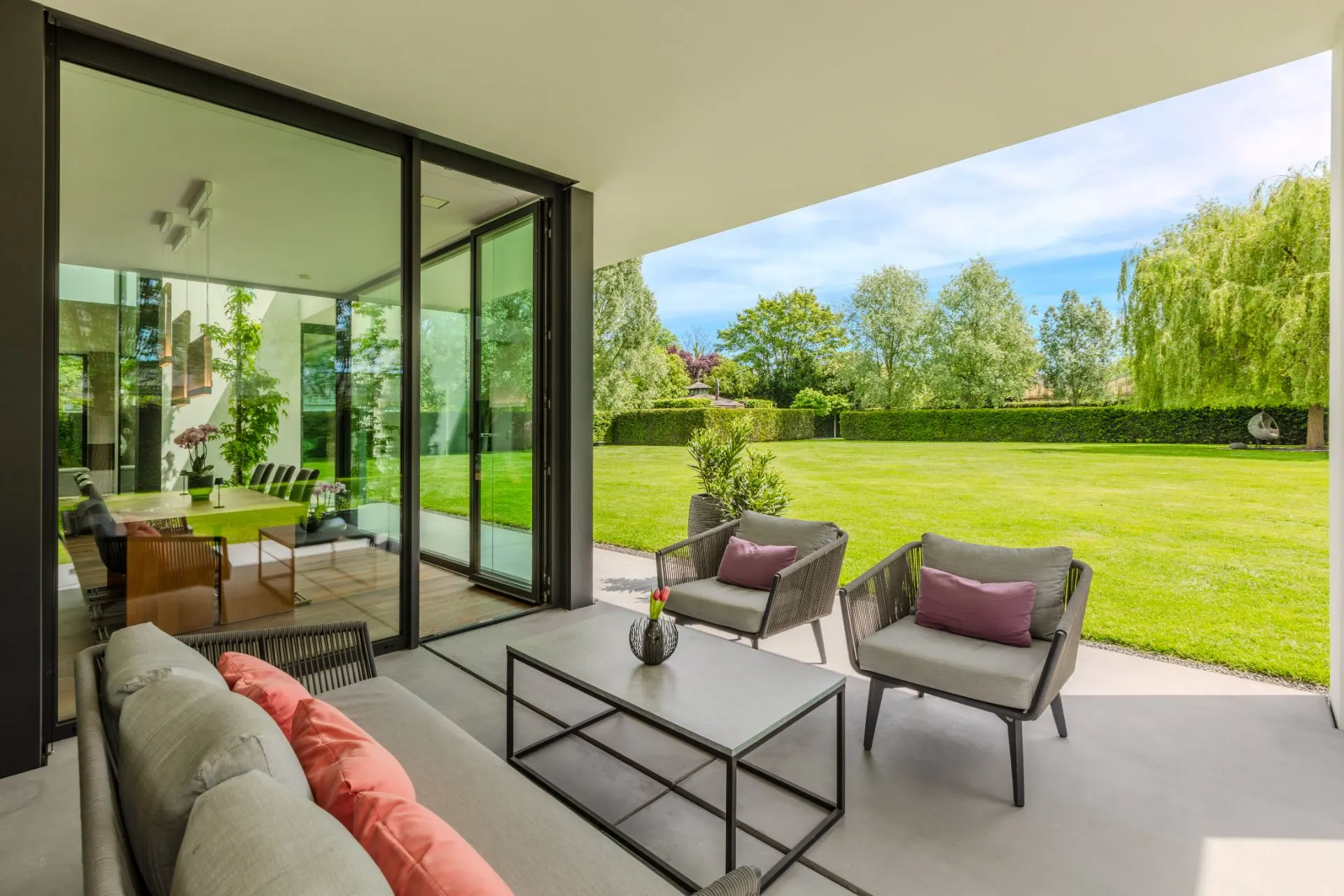 Moderne Terrasse mit Sitzmöbeln und Blick auf einen großen, gepflegten Garten.