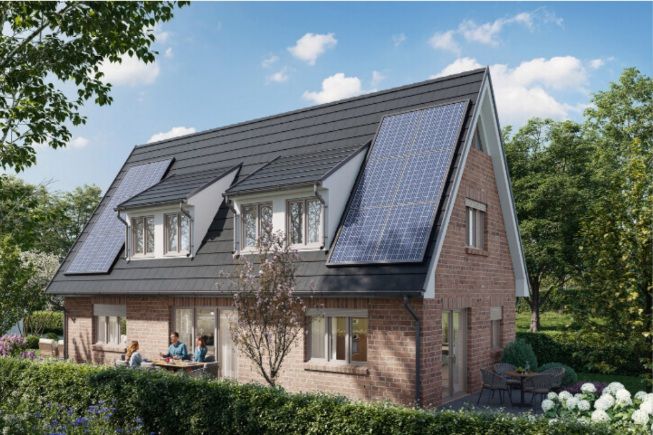 Backsteinhaus mit Solarpaneelen auf dem Dach, Menschen sitzen auf der Terrasse im Garten.