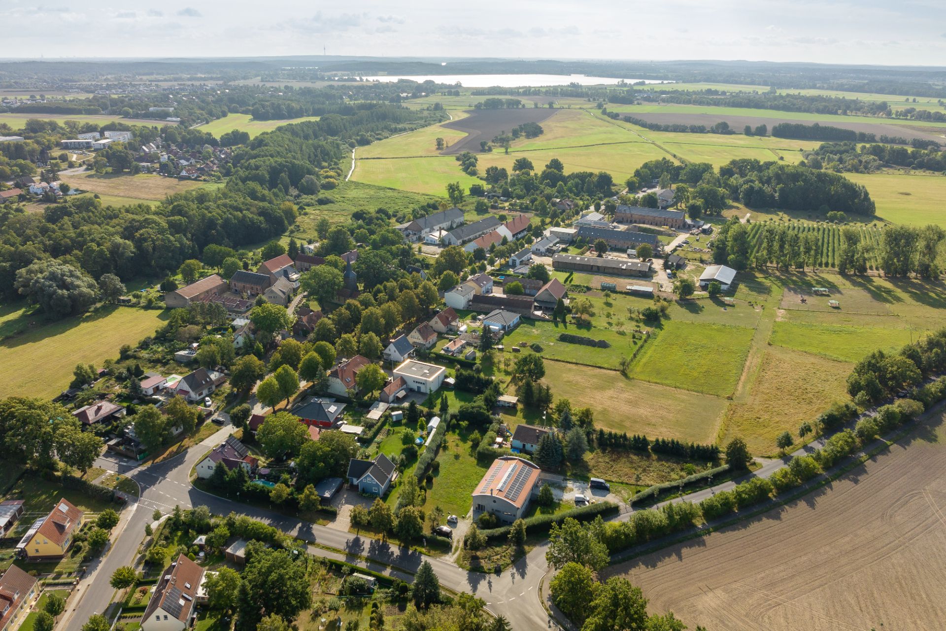 Luftaufnahme eines Wohngebiets mit Häusern, Bäumen und umliegenden Feldern.