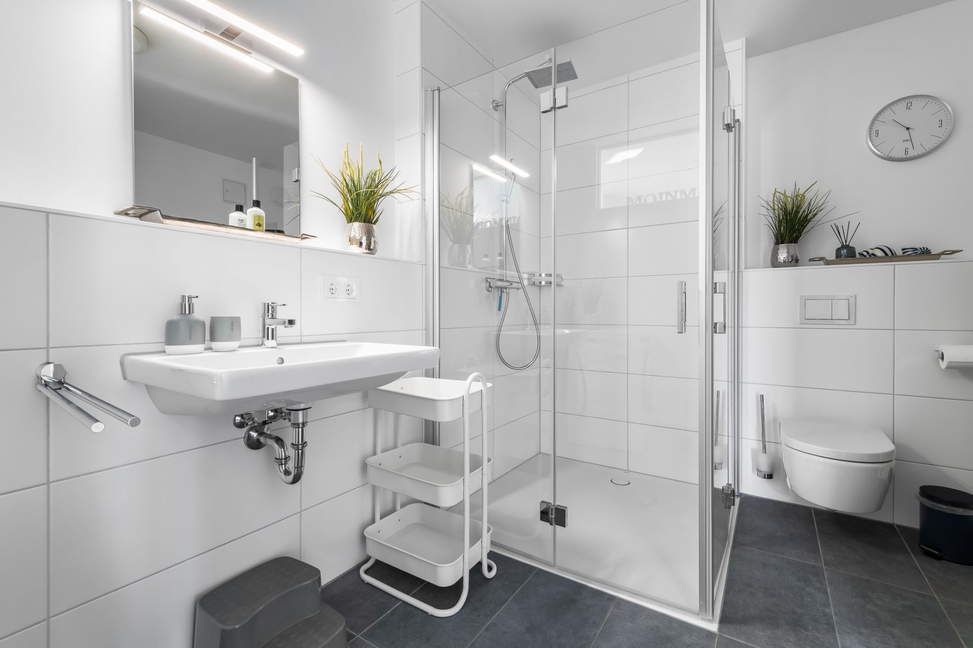 Modernes Badezimmer mit Dusche, Waschbecken, Regal, WC und Wandspiegel.